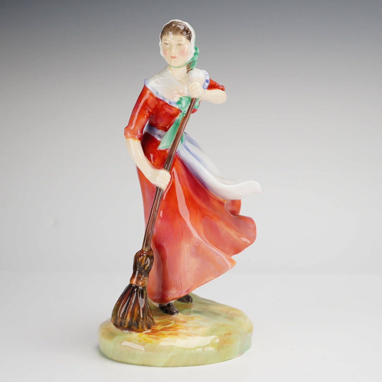 Royal Doulton Autumn Figurine HN2087: A Royal Doulton bone china figurine titled Autumn, model HN2087, from The Seasons series. This vintage piece depicts a woman in a windswept pose wearing a vibrant red dress, a white apron with a pale 