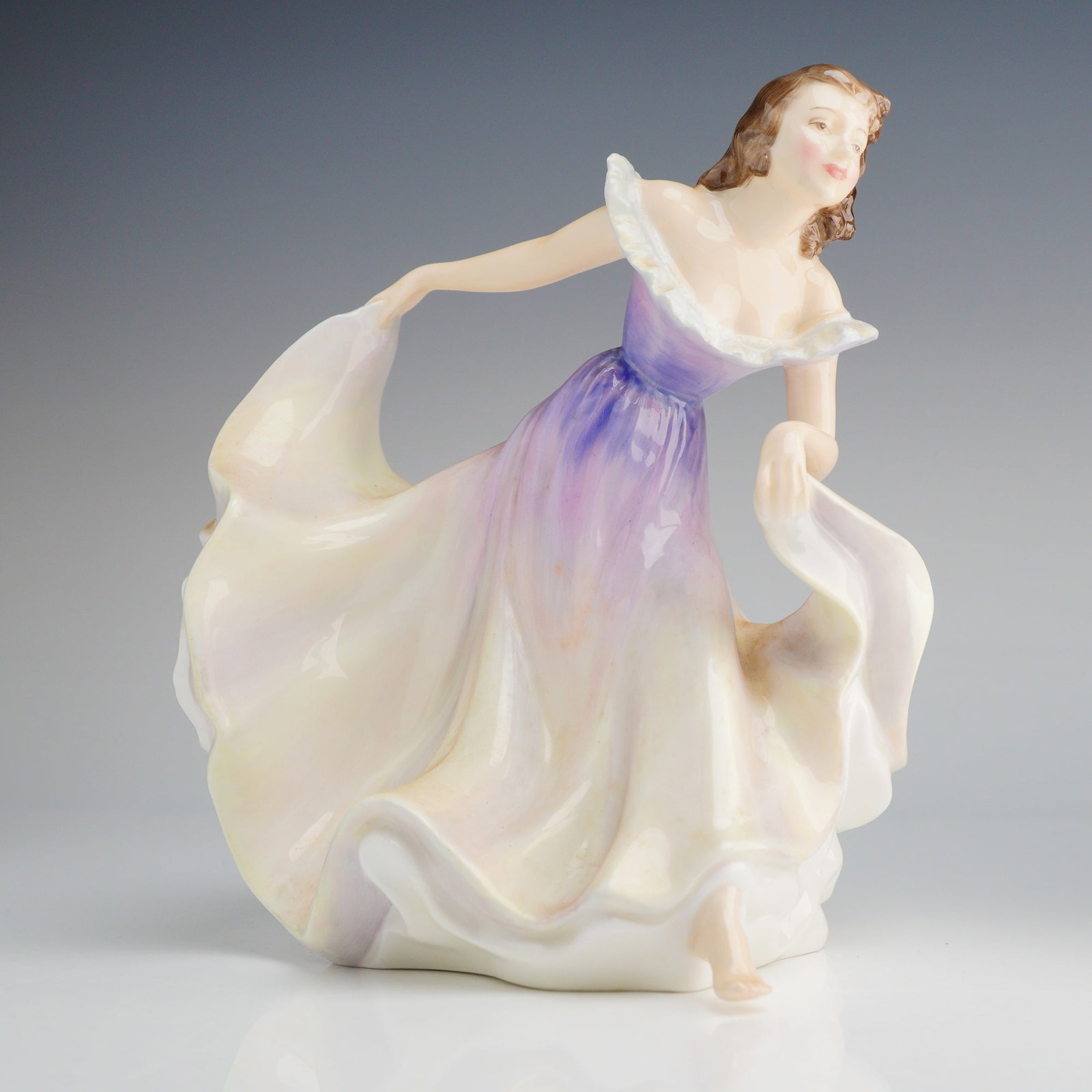 Royal Doulton Figurine Gypsy Dance HN2230: The piece is executed in glazed porcelain or bone china, depicting a female dancer in a dynamic, mid-step pose. The figure is dressed in a formal gown featuring a ruffled off-the-shoulder neckline. Th