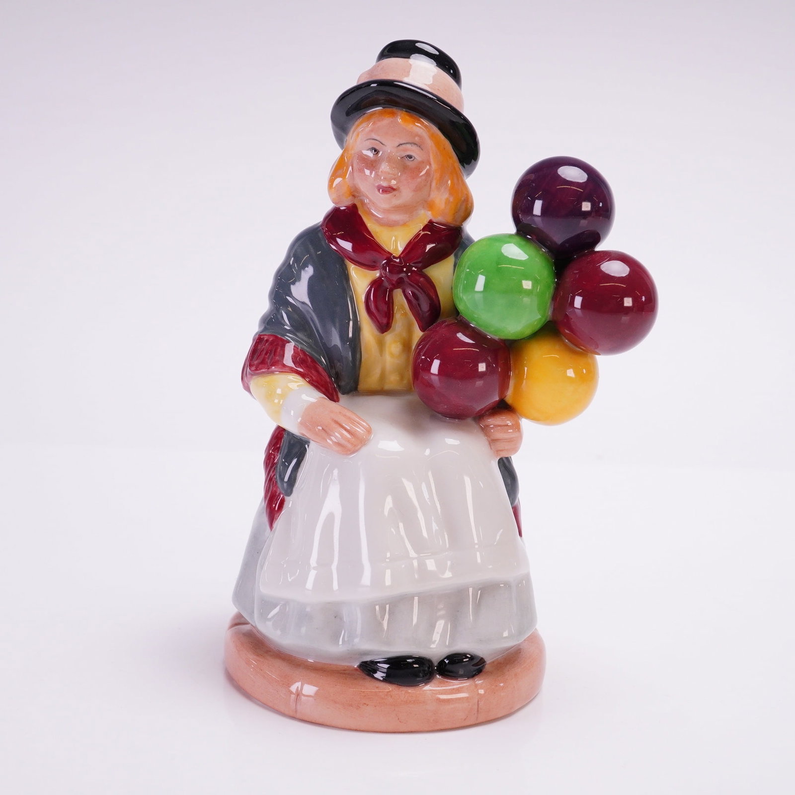 Royal Doulton Figurine, Balloon Girl HN2818: Porcelain figurine designed by William K. Harper. The figure depicts a young girl in a bowler hat and shawl, seated with a colorful cluster of balloons in her hand. Finely hand-painted with vibrant gl