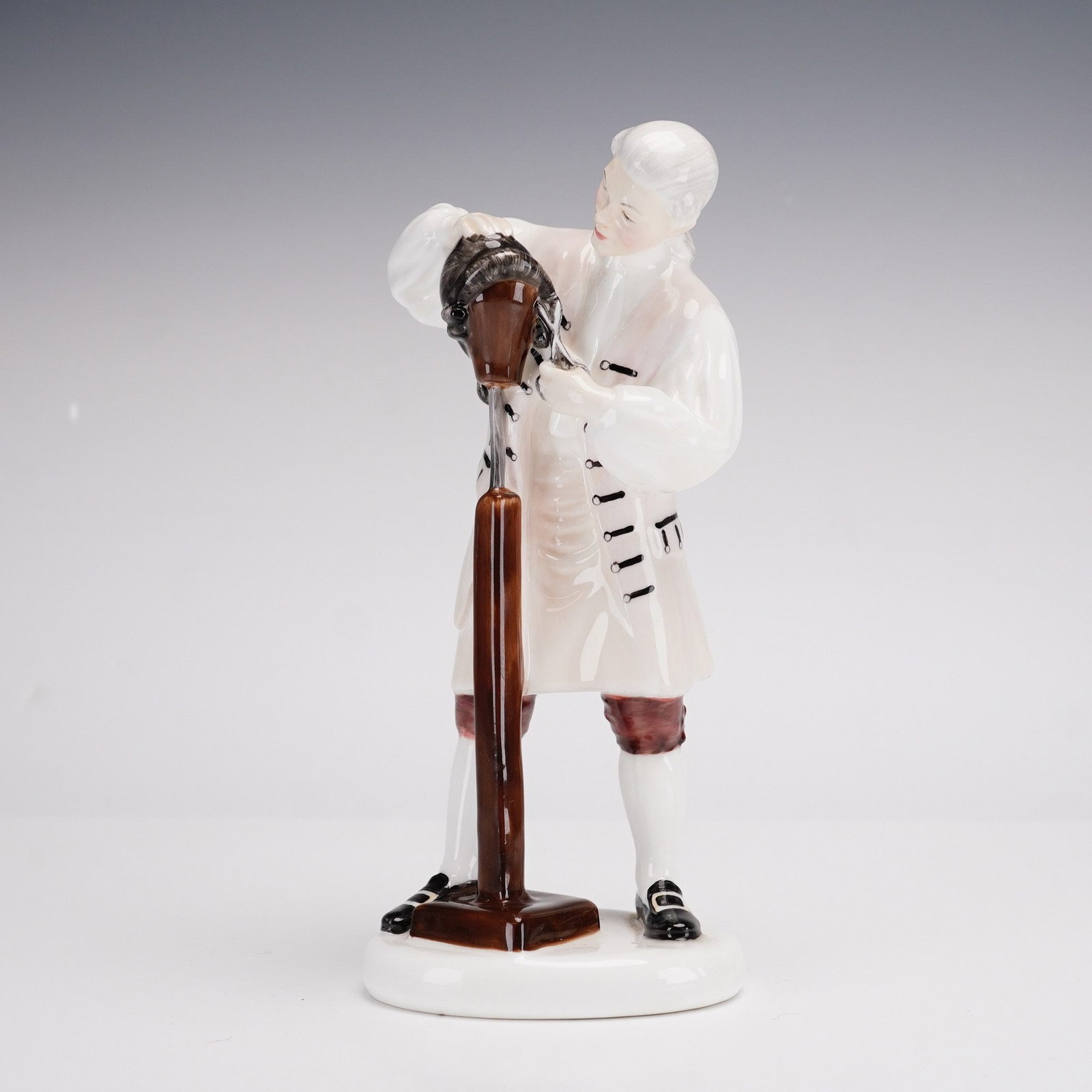 Royal Doulton, The Wigmaker of Williamsburg HN 2239: A Royal Doulton polychrome glazed bone china figurine titled The Wigmaker of Williamsburg, model number HN 2239. Part of the Williamsburg series, the figure depicts a colonial-era craftsman in 18th-ce