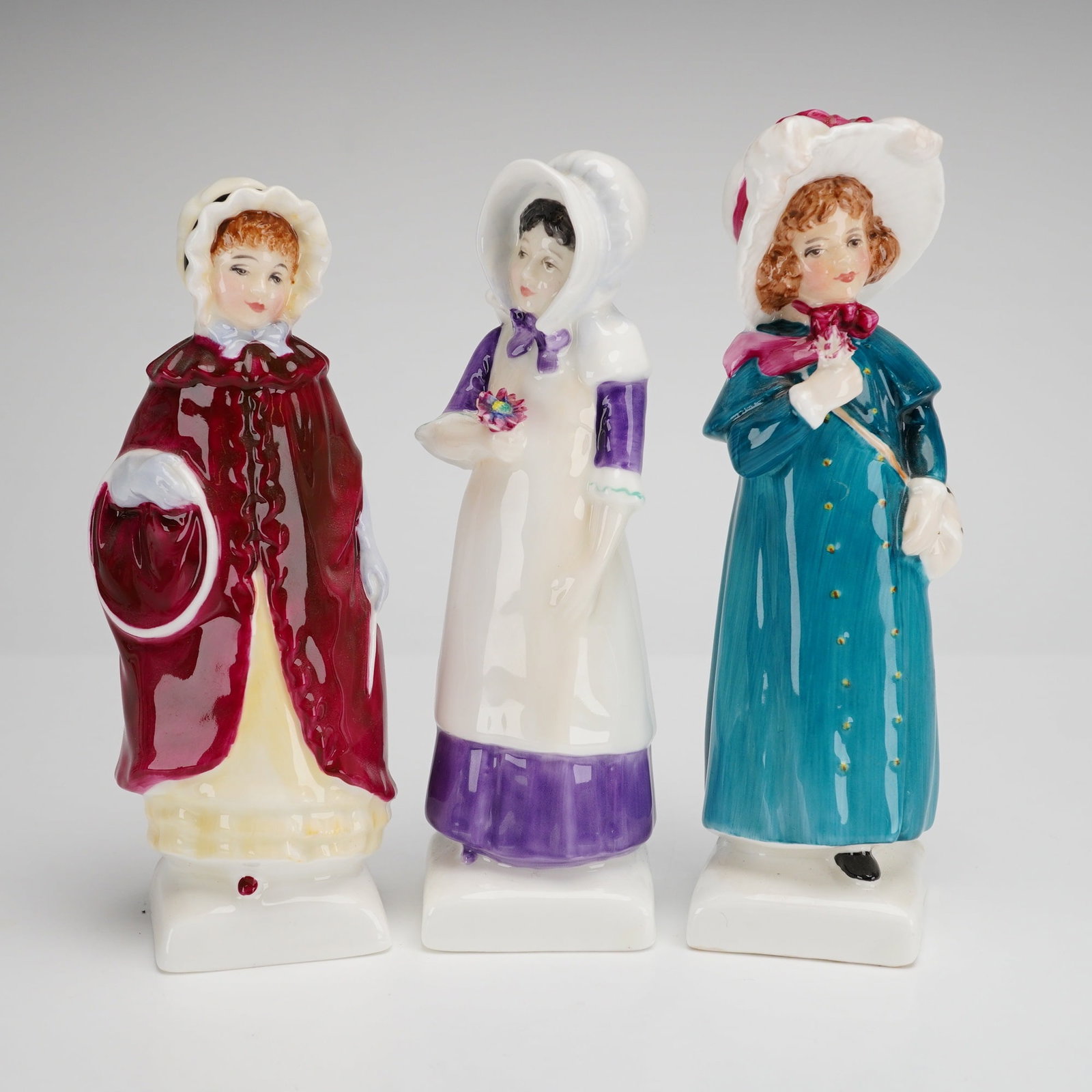 Three Royal Doulton Bone China Figurines, Anna (HN2802), Carrie (HN2800), and Georgina (HN2377): Three Royal Doulton bone china figurines from the Kate Greenaway Collection, manufactured in England. This group includes the models Anna (HN 2802), Carrie (HN 2800), and Georgina (HN 2377). Each figu