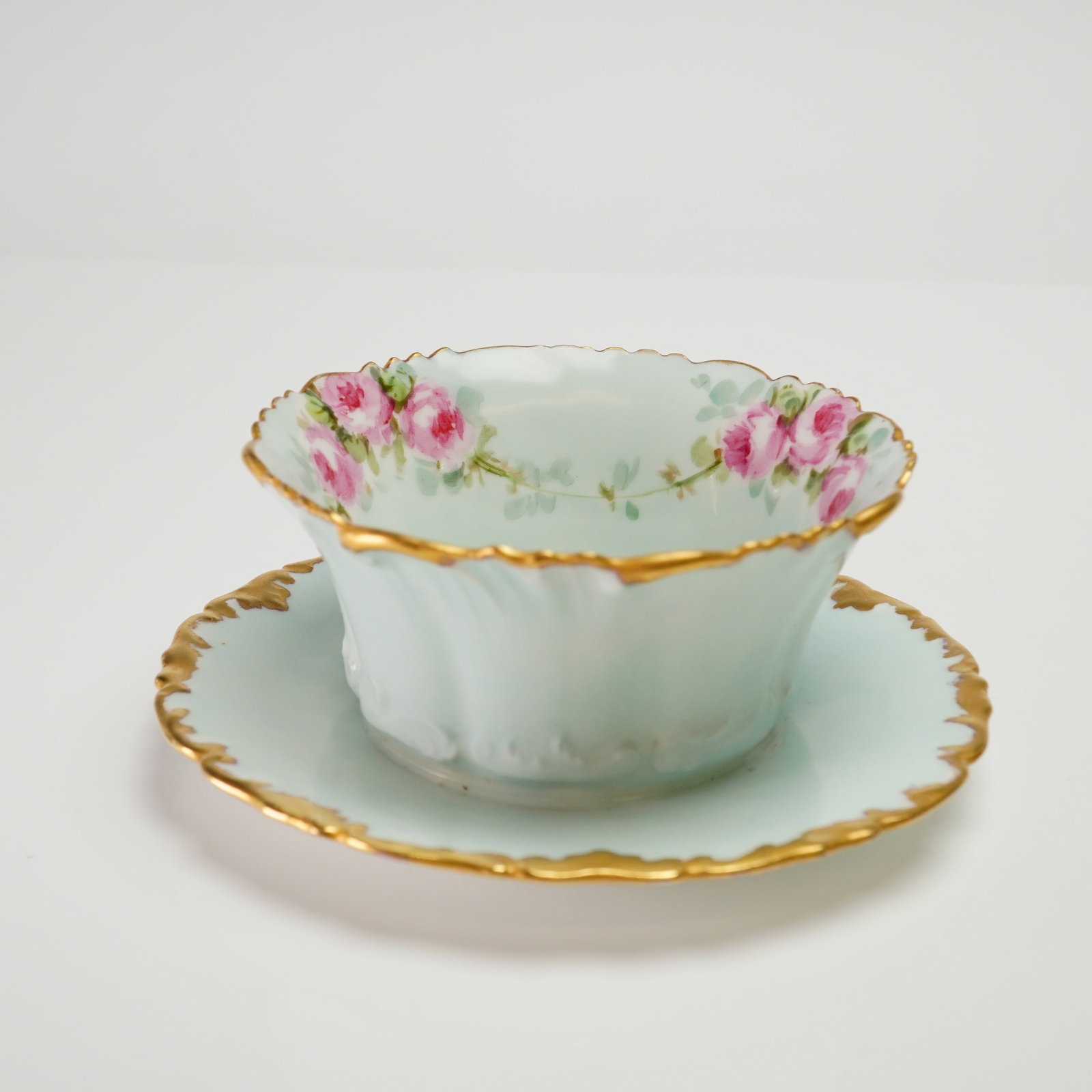 T&V Limoges France Porcelain Bowl with Attached Underplate: A Tressemann and Vogt (T&V) Limoges porcelain bowl with an attached underplate. The piece features a pale mint-green glaze on the bowl exterior and the upper surface of the underplate. The interior ri