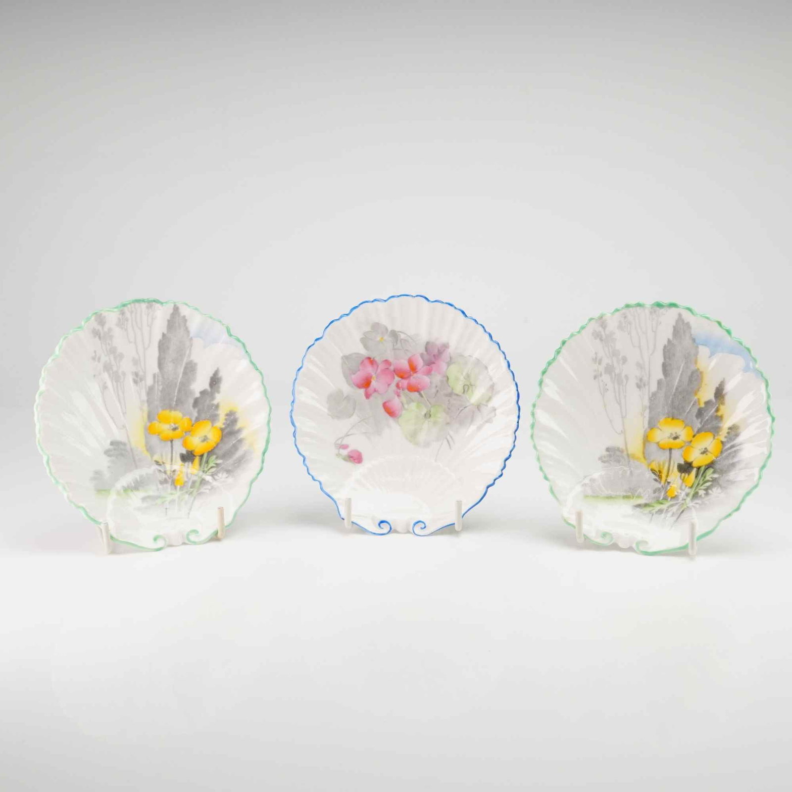3pc Shelley England Shell Dishes: This collection of English fine bone china consists of three small Shelley England shell dishes with floral designs. Two of these fluted dishes feature yellow poppies with gray foliage and green scall