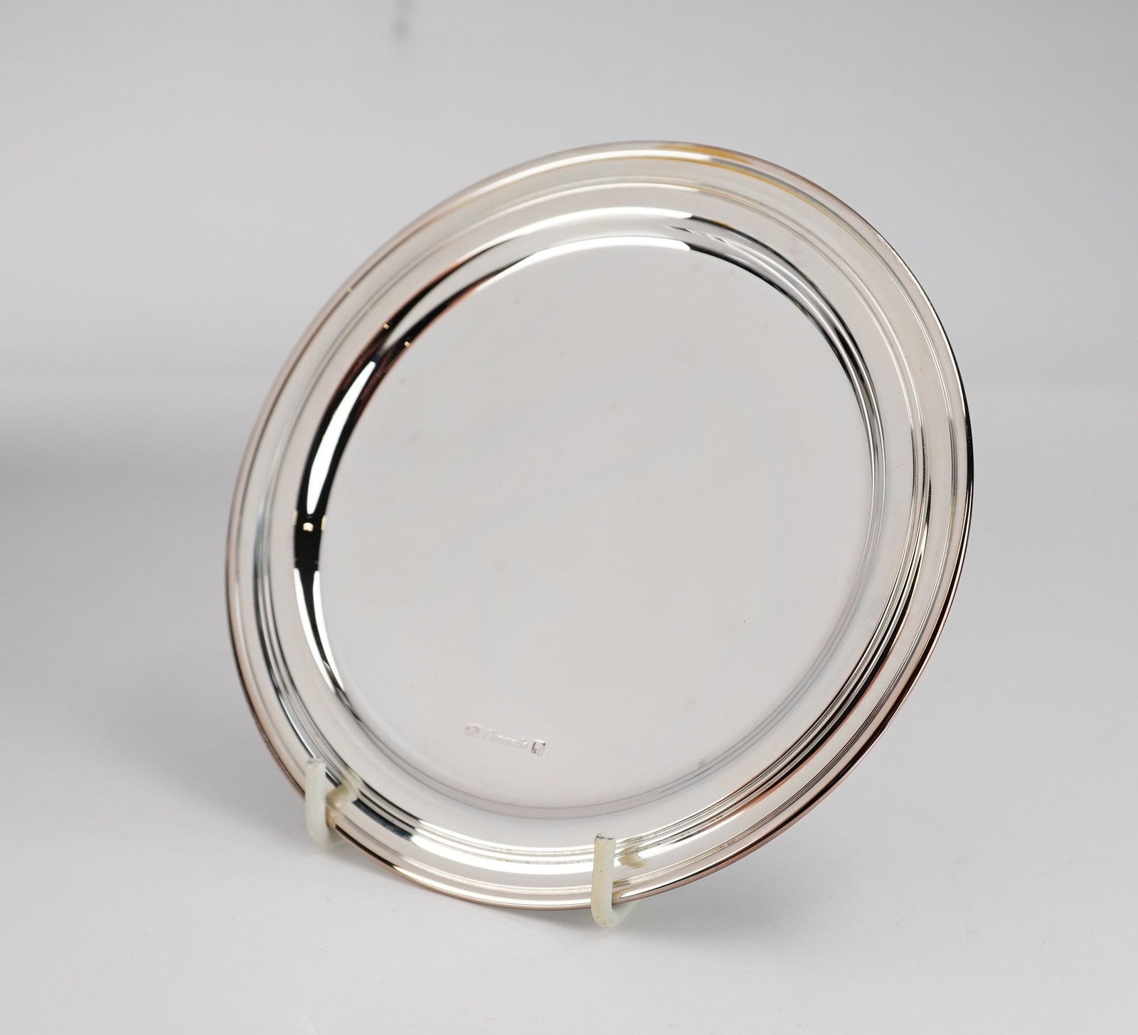 Christofle Albi Silver-Plated Round Platter: A Christofle silver-plated round platter in the Albi pattern. The piece features a minimalist, modernist design with a wide rim decorated by three tiered, concentric circular moldings. The central wel