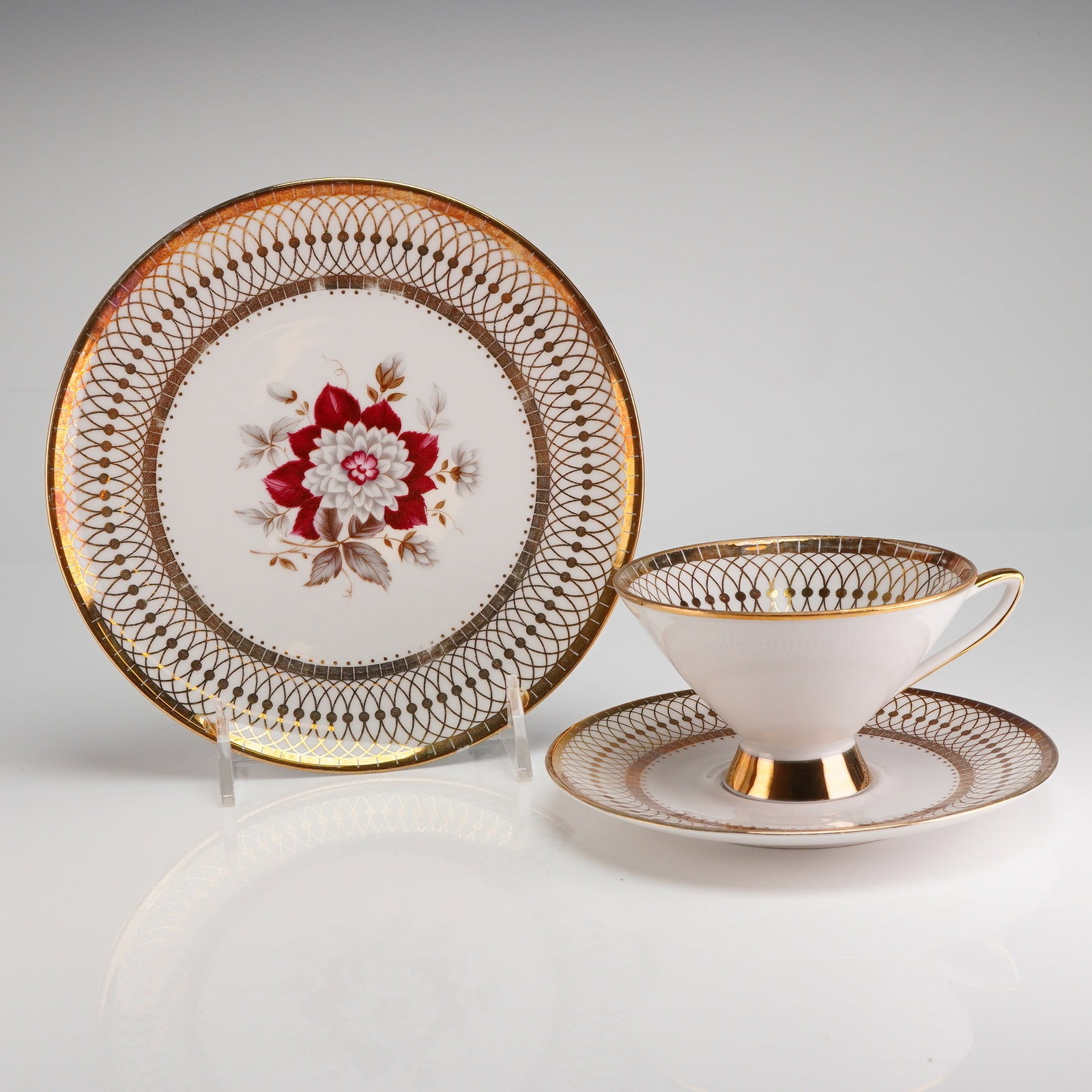 Winterling Bavaria Porcelain Trio Tea Set, Roslau: The set comprises one teacup, one saucer, and one dessert plate. The white porcelain body is decorated with heavy gold gilding applied in a reticulated lattice pattern around the rims and interior sur