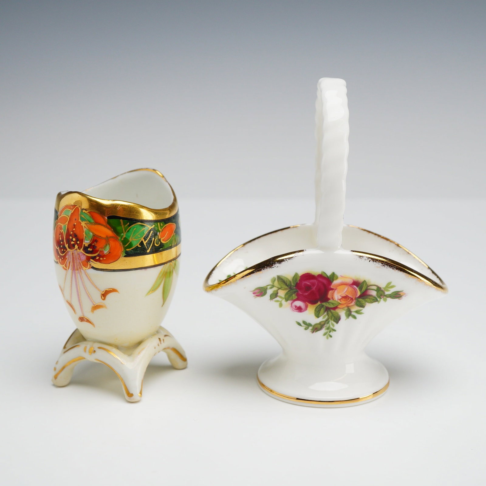 Lot of Two Royal Albert Old Country Roses Basket and Bavarian Egg Cup: This lot features two small decorative ceramic items. The first item is a Bavarian porcelain egg cup designed with an egg-shaped body and an asymmetrical flared rim, resting on three scrolled feet. Th