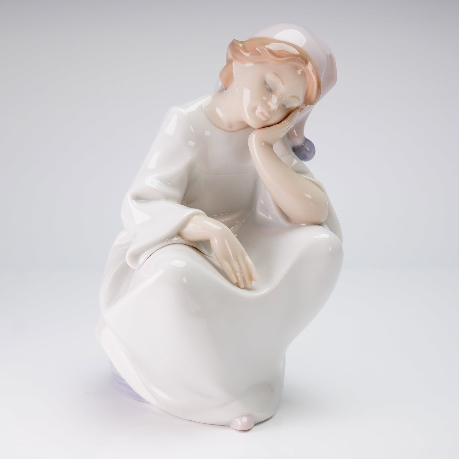 Lladro Figurine Just Resting 6481: A Lladro figurine, model number 6481, titled "Just Resting." This single glazed porcelain figurine depicts a youth or child sleeping while seated on a lavender and white patterned drum or stool. The