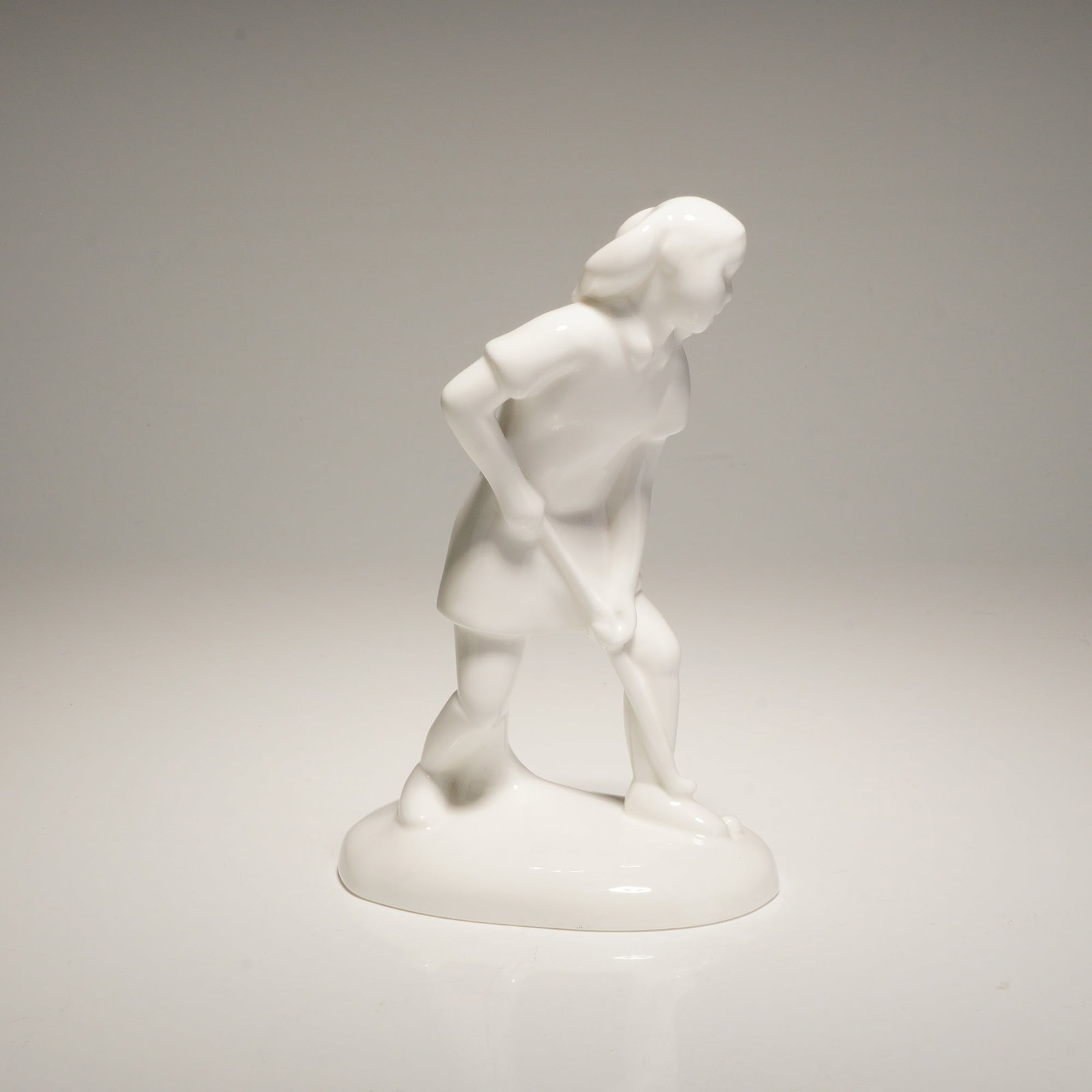 Royal Doulton Bone China Figurine, Hockey Player HN4519: This hand-made sculpture depicts a stylized field hockey player in an athletic pose, designed in a minimalist style with an all-over high-gloss white glaze. The underside of the integrated oval base f