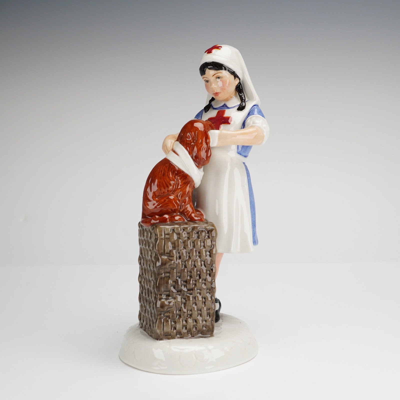 Royal Doulton Childhood Days It Won't Hurt HN2963 Figurine: A Royal Doulton glazed porcelain figurine titled It Won't Hurt, model HN2963, from the Childhood Days series. This hand-decorated piece depicts a young girl in a nurse's uniform with a red cross emble