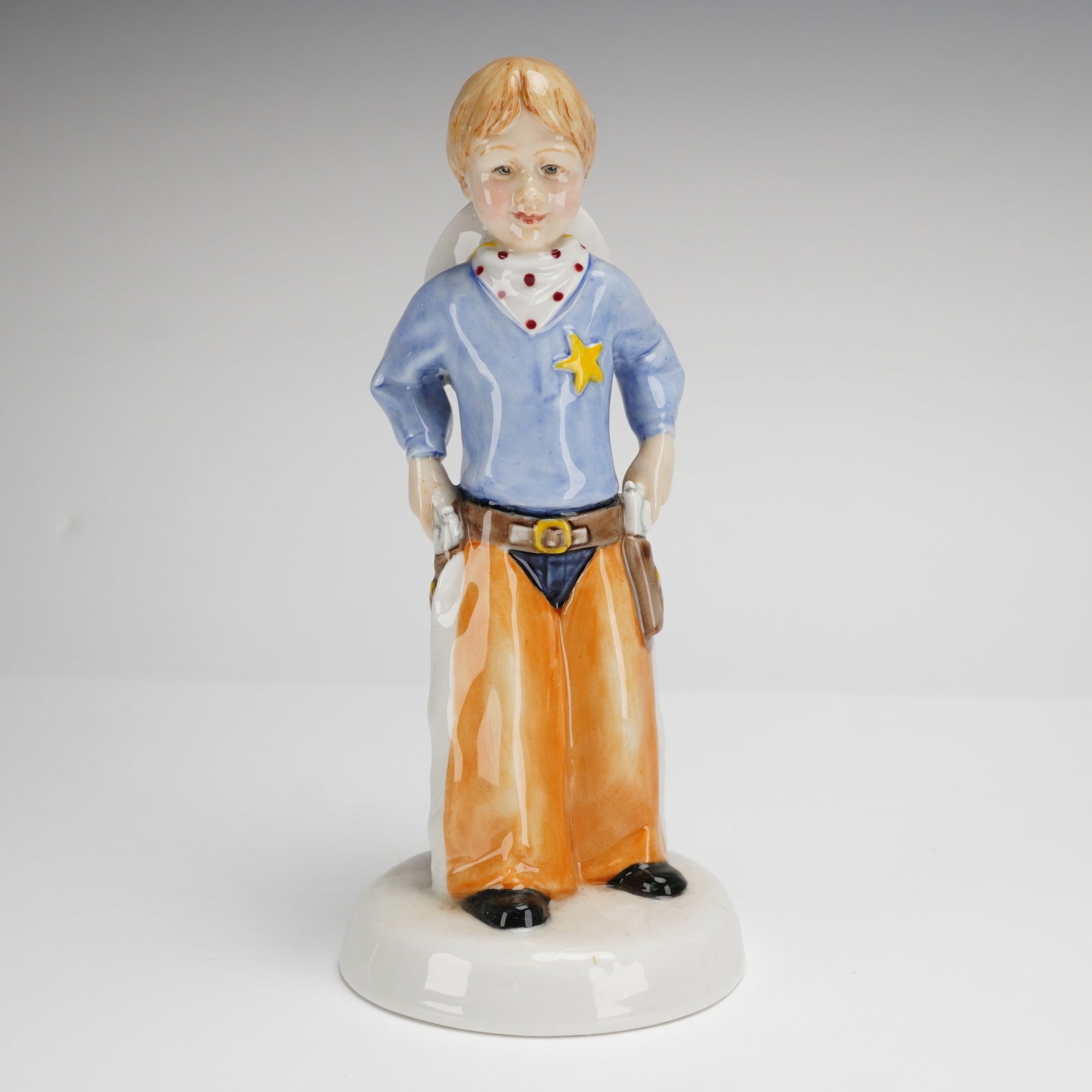 Royal Doulton Childhood Days Stick 'Em Up HN2981: A Royal Doulton glazed porcelain figurine titled Stick 'Em Up HN 2981 from the Childhood Days series, modeled by Adrian Hughes. The figure depicts a young boy in a cowboy costume, featuring a blue shi