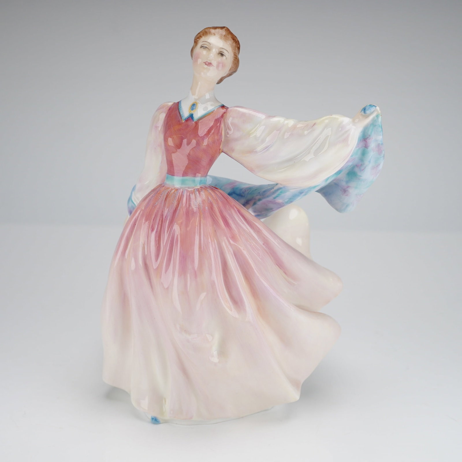 Royal Doulton Figurine Gay Morning HN2135: A single bone china figurine by Royal Doulton, titled 'Gay Morning,' model number HN 2135. The figurine depicts a dramatically posed woman, likely dancing, wearing a voluminous, ruffled gown shaded pr