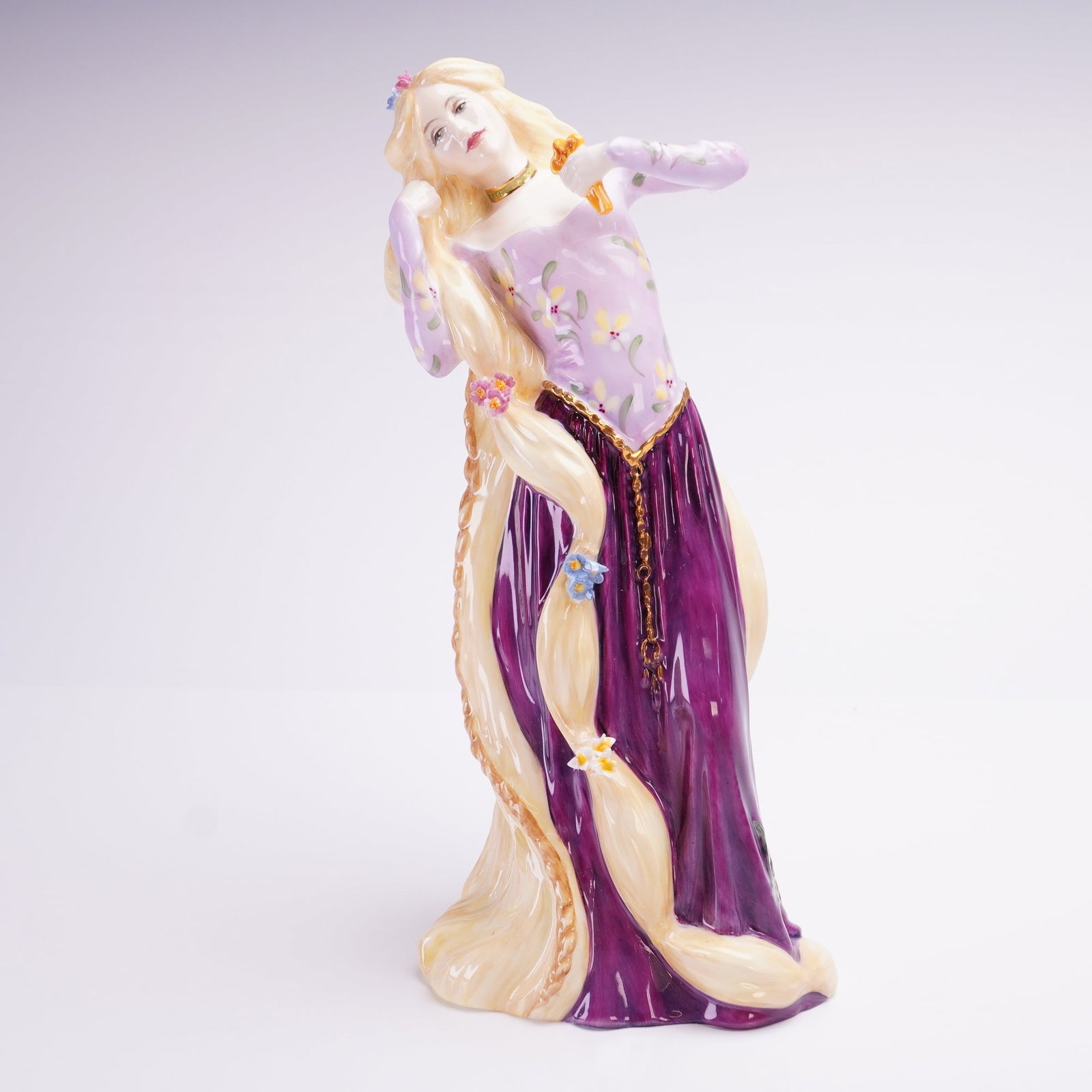 Royal Doulton Figurine Rapunzel HN3841: A Royal Doulton bone china figurine titled Rapunzel HN3841 modeled by P. Parsons and issued in 1997 as part of a limited edition. The figure depicts the fairytale character with long blonde hair adorn