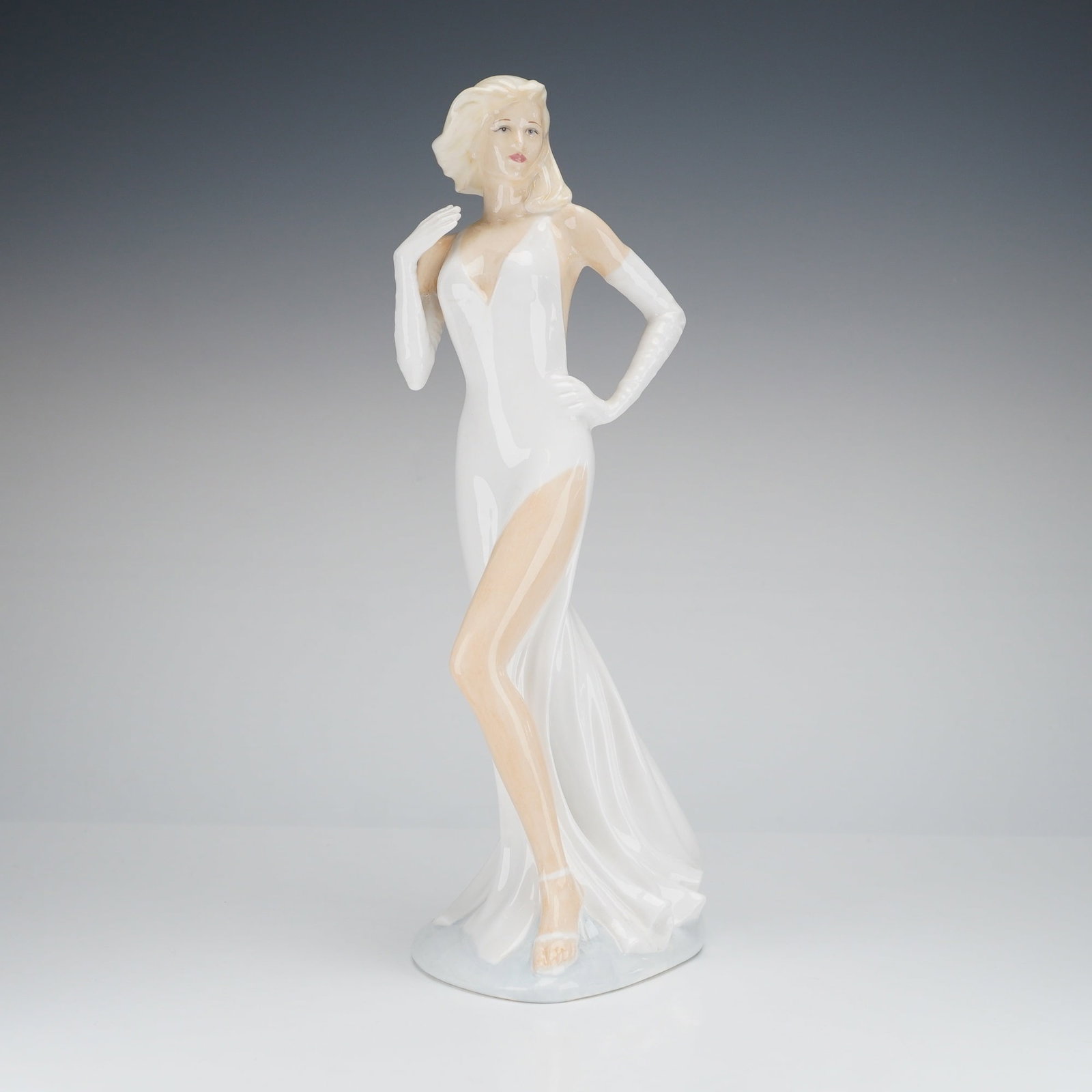 Royal Doulton Figurine Simone HN 4535: The bone china figurine, titled Simone is part of The Sensual Collection. The hand-made and hand-decorated figure depicts a female figure in a dynamic pose, dressed in a high-slit, low-back white gown