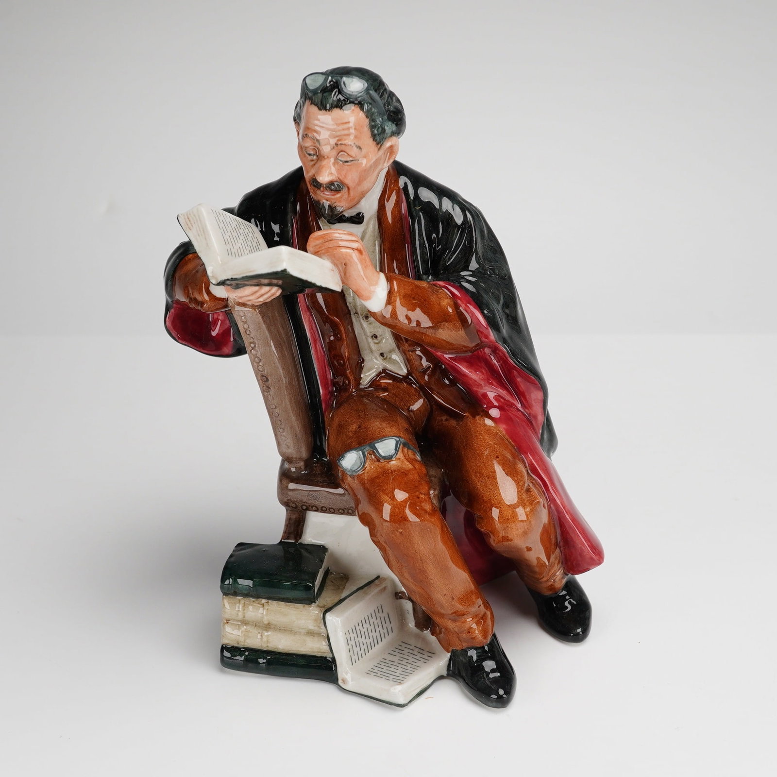 Royal Doulton Figurine The Professor HN2281: A Royal Doulton porcelain figurine titled The Professor, model number HN2281, designed by M. Nicoll. This glazed polychrome ceramic figure depicts a seated male in mid-20th-century academic attire, we