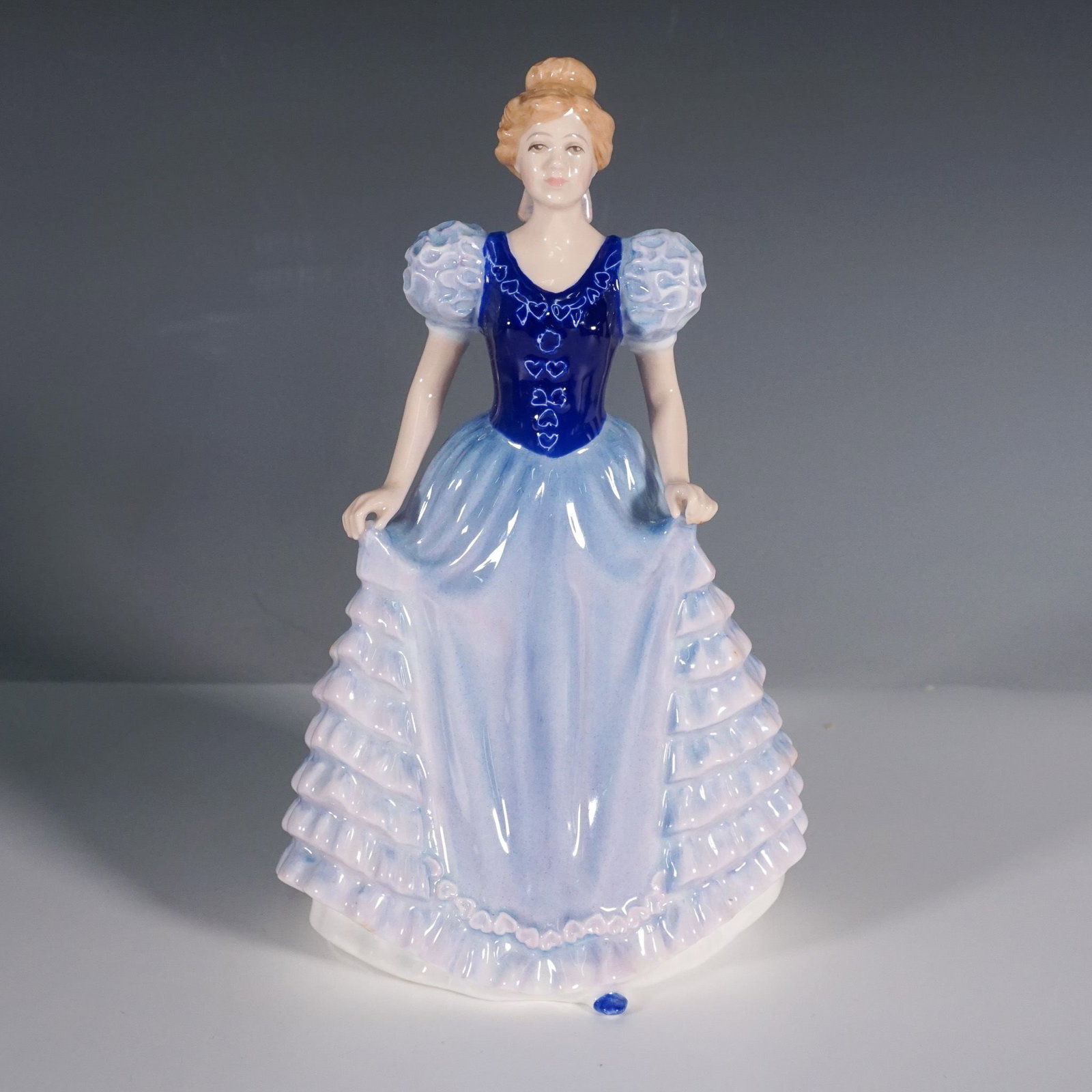 Royal Doulton Figurine, Charlotte HN 3658: This Royal Doulton figurine, Charlotte HN 3658, is a finely crafted porcelain piece designed by Nada M. Pedley. Issued in 1994, this elegant figurine features a young woman in a flowing blue gown with
