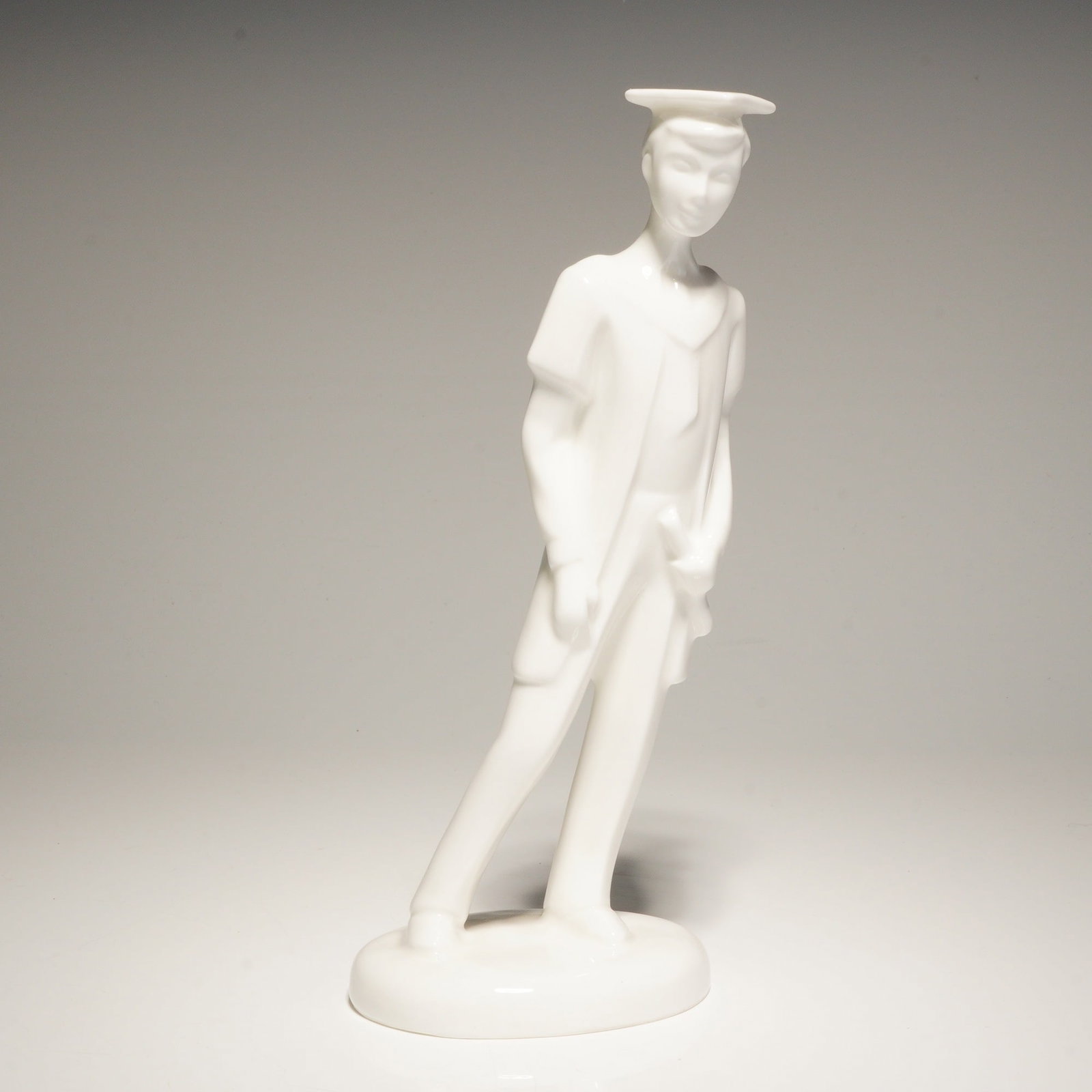 Royal Doulton Images Figurine, Graduate Male HN4543: The piece features a minimalist, stylized design with a monochromatic white glaze. It depicts a male figure in graduation attire, including a mortarboard and gown. The base is marked with the Royal Do