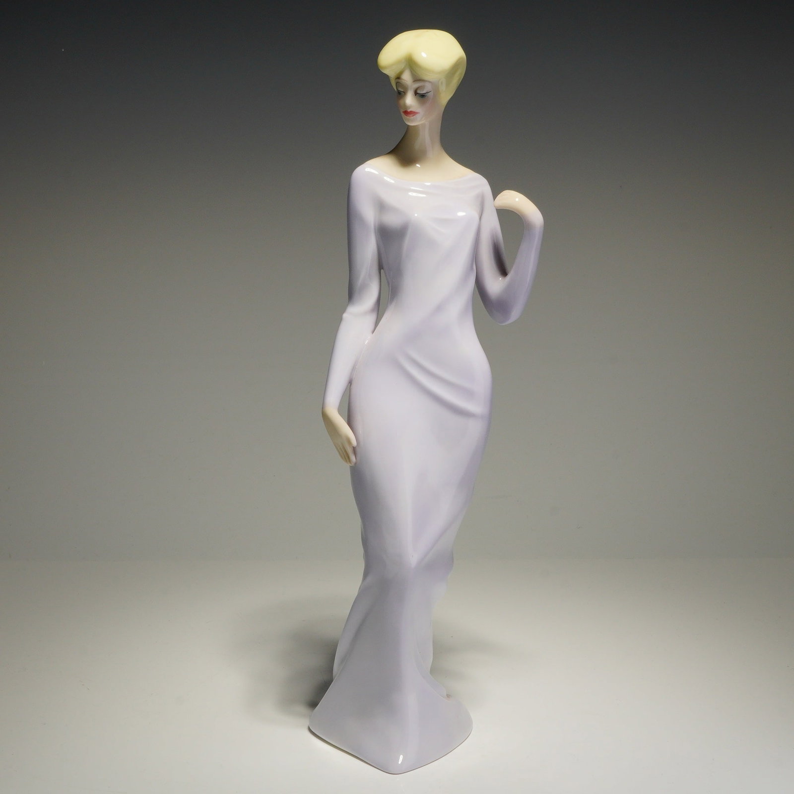 Royal Doulton Reflections Figurine, Debutante HN3188: This Royal Doulton glazed ceramic figurine, titled Debutante (HN 3188) from the Reflections series, was modeled by Eric J. Griffiths and is dated 1988. The figure depicts a stylized woman with blonde 