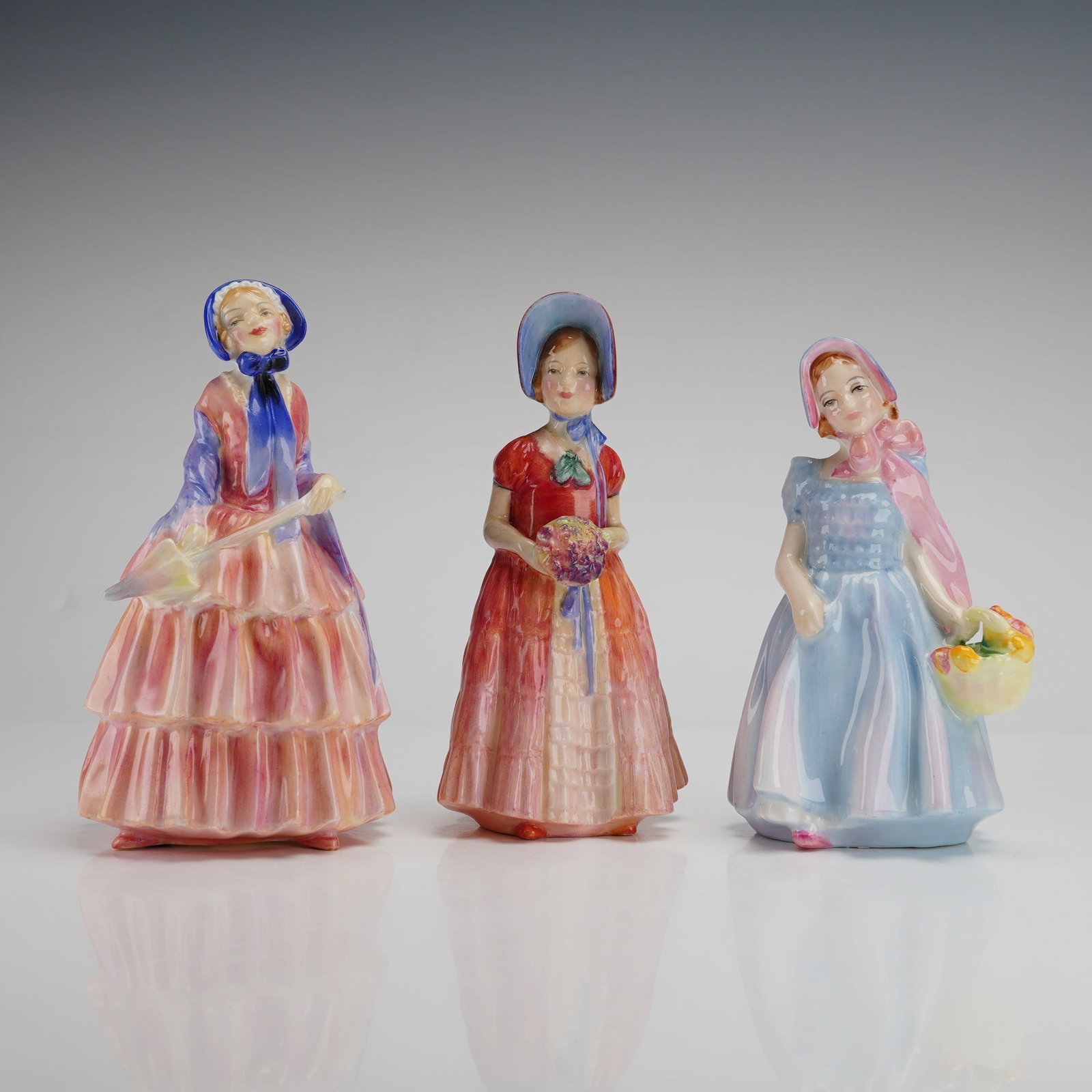 3pc Royal Doulton Bone China Figurines, Biddy, Diana, and Wendy: A trio of hand-painted glazed bone china figurines produced by Royal Doulton in England. The group consists of the models Biddy, Diana, and Wendy. Biddy, model HN1513, is depicted in a tiered pink dre