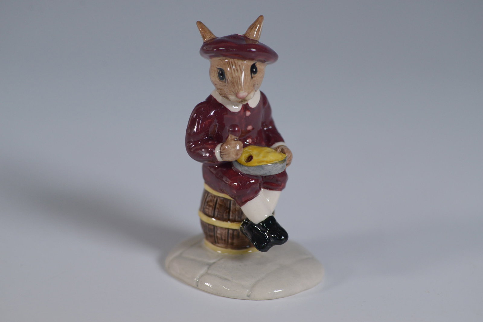 Royal Doulton Bunnykins Figurine, Little Jack Horner DB221: Charming Royal Doulton Bunnykins figurine titled Little Jack Horner, model DB221. This hand-painted porcelain piece features a whimsical rabbit seated on a barrel, dressed in a rich burgundy outfit wi