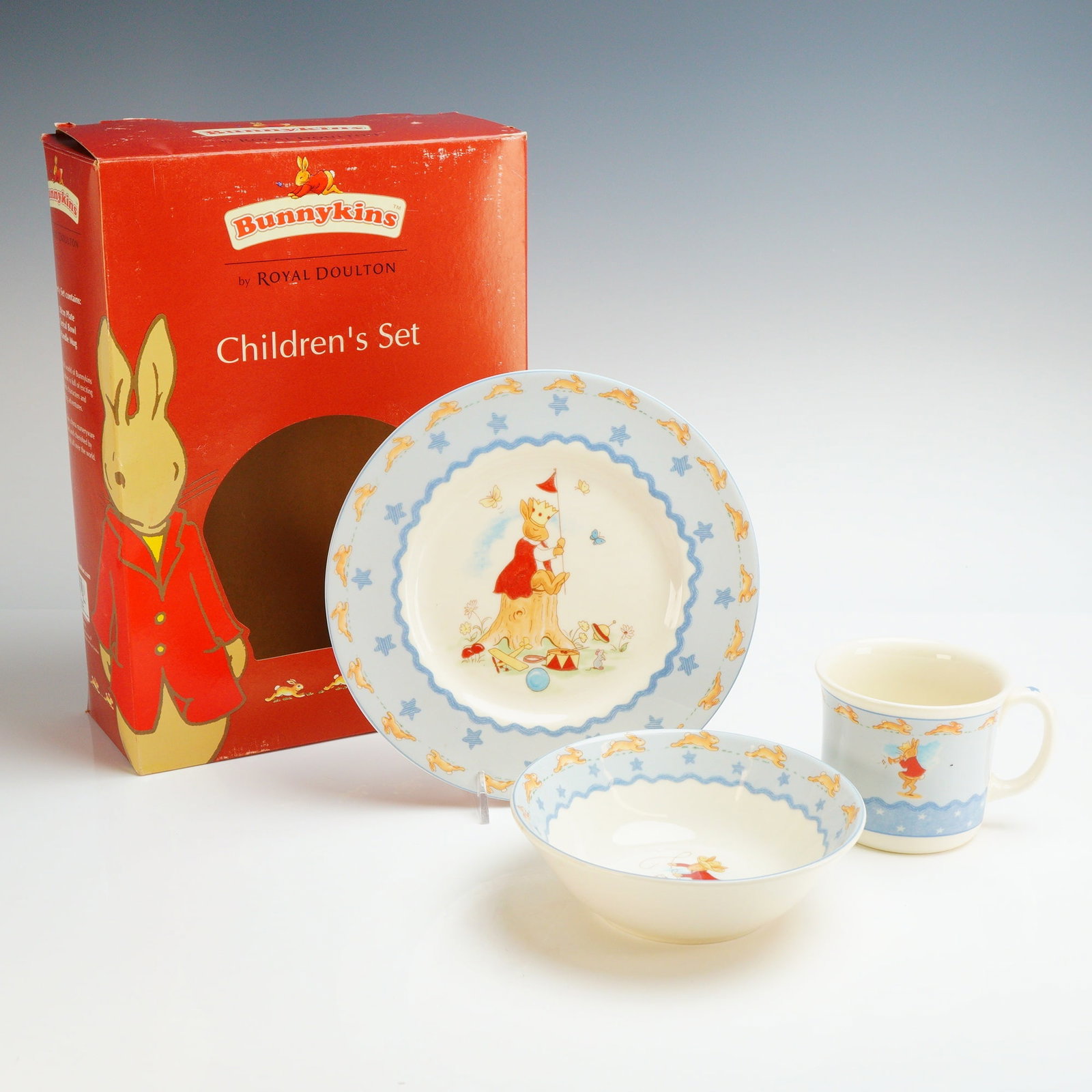 Royal Doulton Bunnykins Shining Stars 3-Piece Children's Nurseryware Set: The set is manufactured from bone china and includes a plate, a bowl, and a single-handled mug. The pieces feature transfer-printed illustrations of rabbits in various scenes, including a crowned rabb