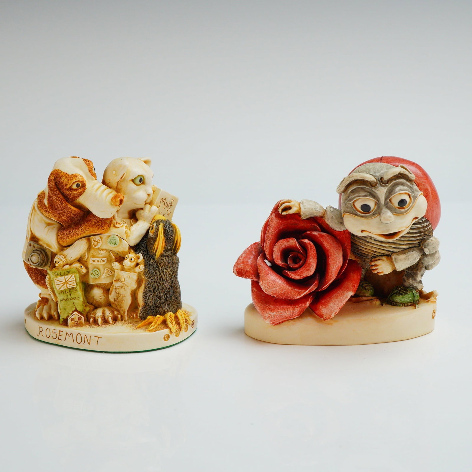 2pc Harmony Kingdom Box Figurines, Signing Line & Byron's Lonely-Heart Club: The first figurine, Signing Line, is marked Atlanta 2000 on the base and features a group of animals including a dog and a cat. The sculpture incorporates various miniature brand logos such as Swarovs
