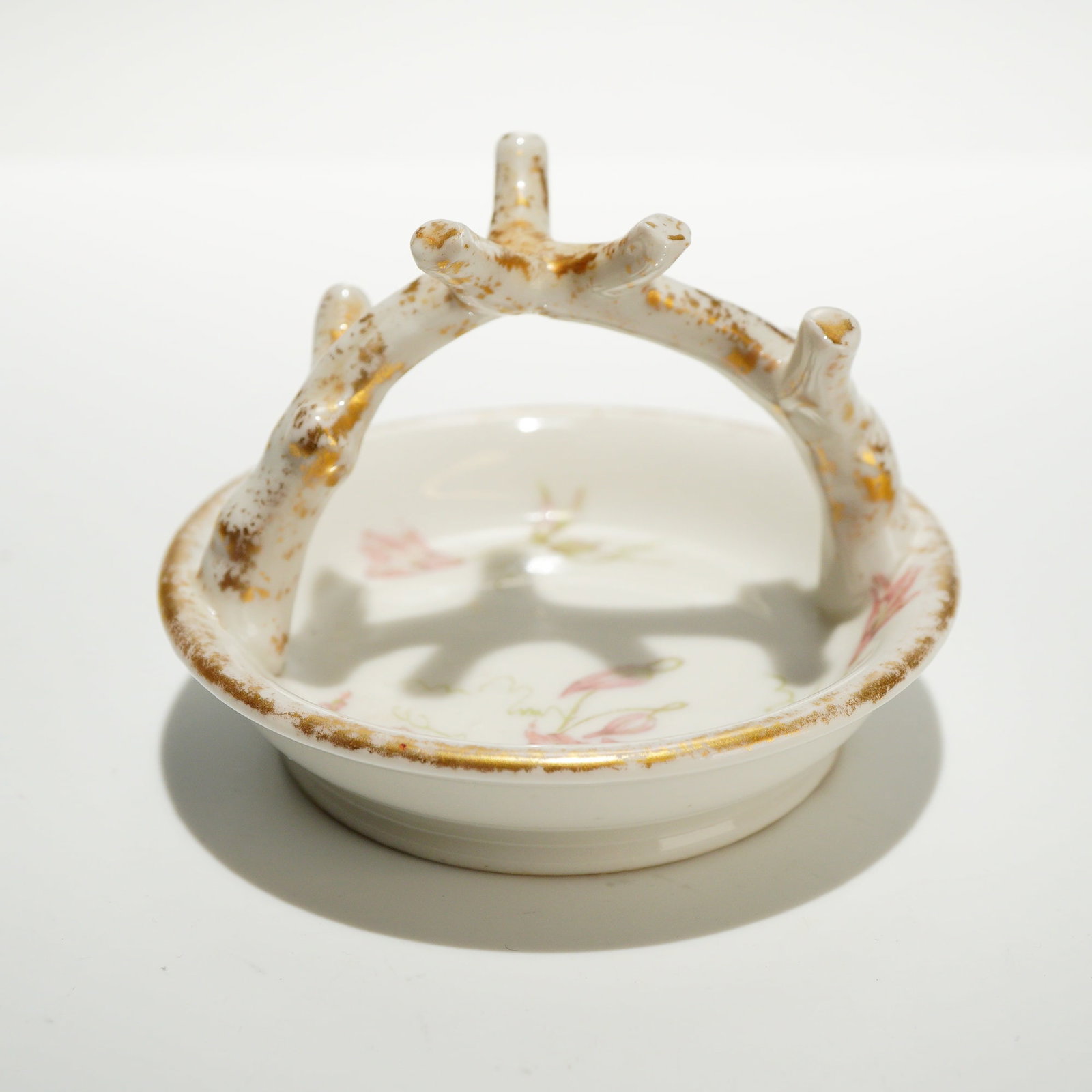 Limoges France Porcelain Floral Ring Tree: This porcelain ring tree features a circular dish base with an arched handle designed in the form of a five-point branch. The interior of the dish is decorated with a floral motif featuring pink bloss