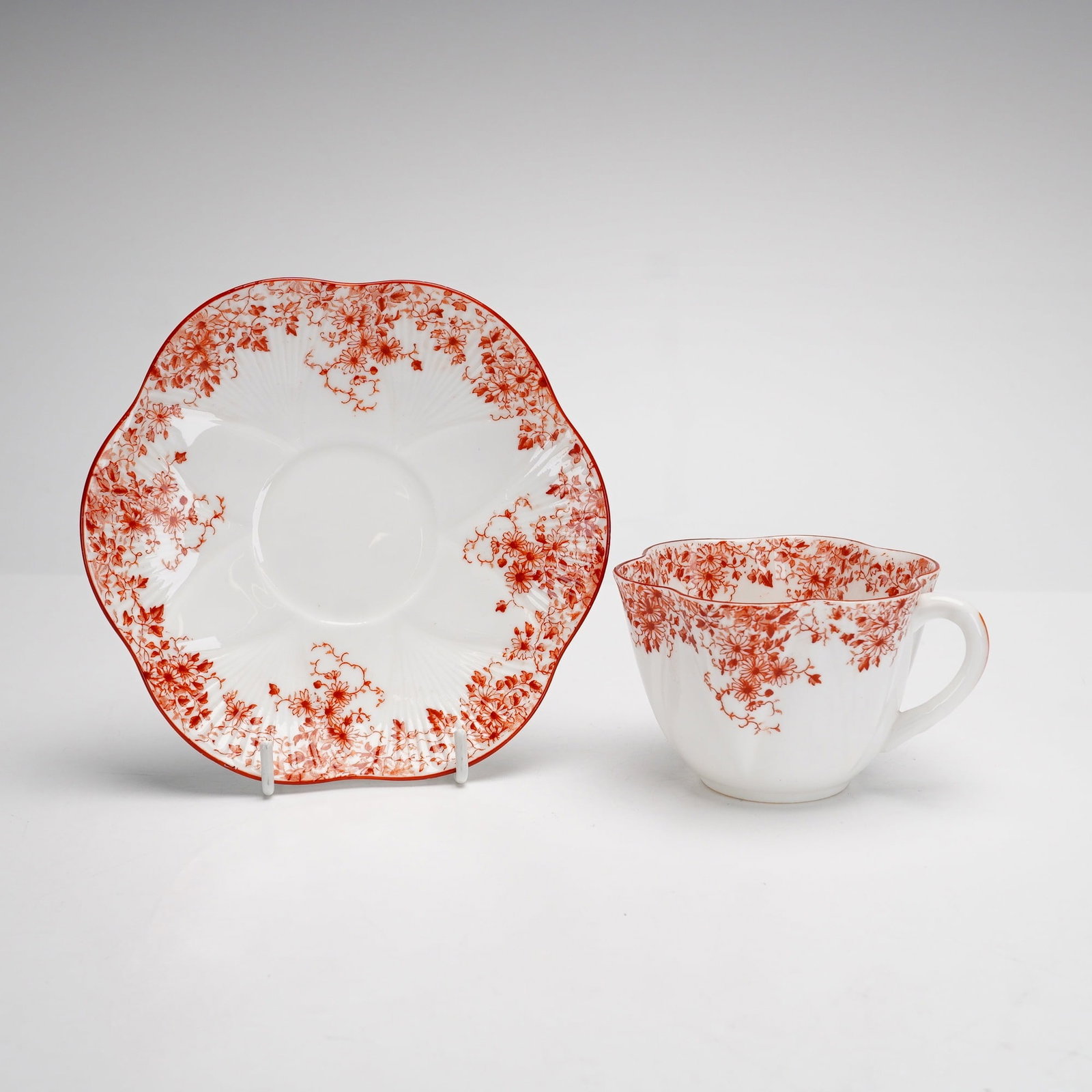 Shelley Cup and Saucer in Dainty Shape with Maroon Floral Pattern: This lot consists of two pieces of Shelley fine bone china, including a teacup and a matching saucer. Both items are in the Dainty shape, which is characterized by lobed, scalloped edges that resemble