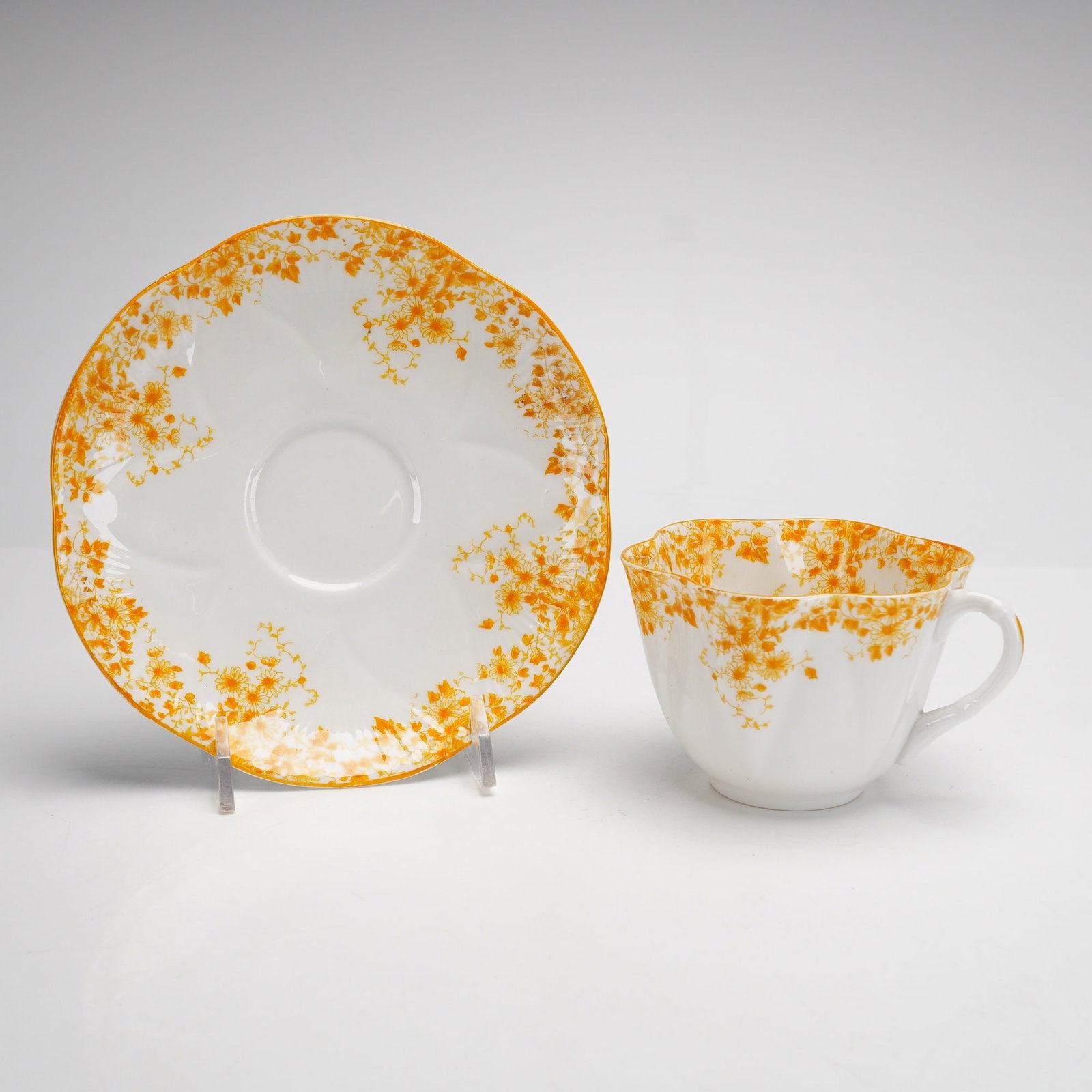 Shelley England Dainty Yellow Fine Bone China Teacup and Saucer: This lot of 2 items features a fine bone china teacup and matching saucer produced by Shelley Potteries of Staffordshire, England. Both pieces are designed in the Dainty shape, notable for its scallop