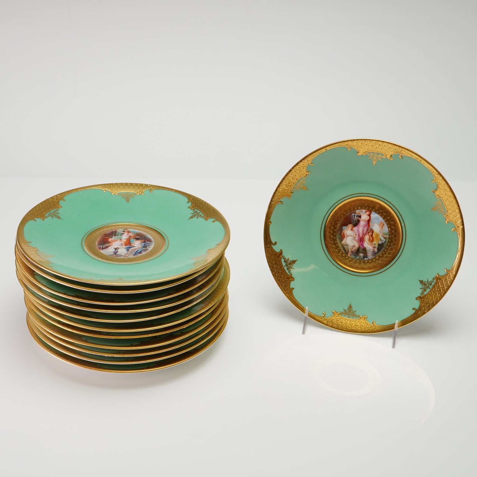 A Set of Twelve Carlsbad Czechoslovakia Hand-Painted Porcelain Dessert Plates: This set of twelve porcelain dessert or salad plates was produced in the Carlsbad region of Bohemia, Czechoslovakia. Each plate features a wide seafoam green border embellished with elaborate raised g