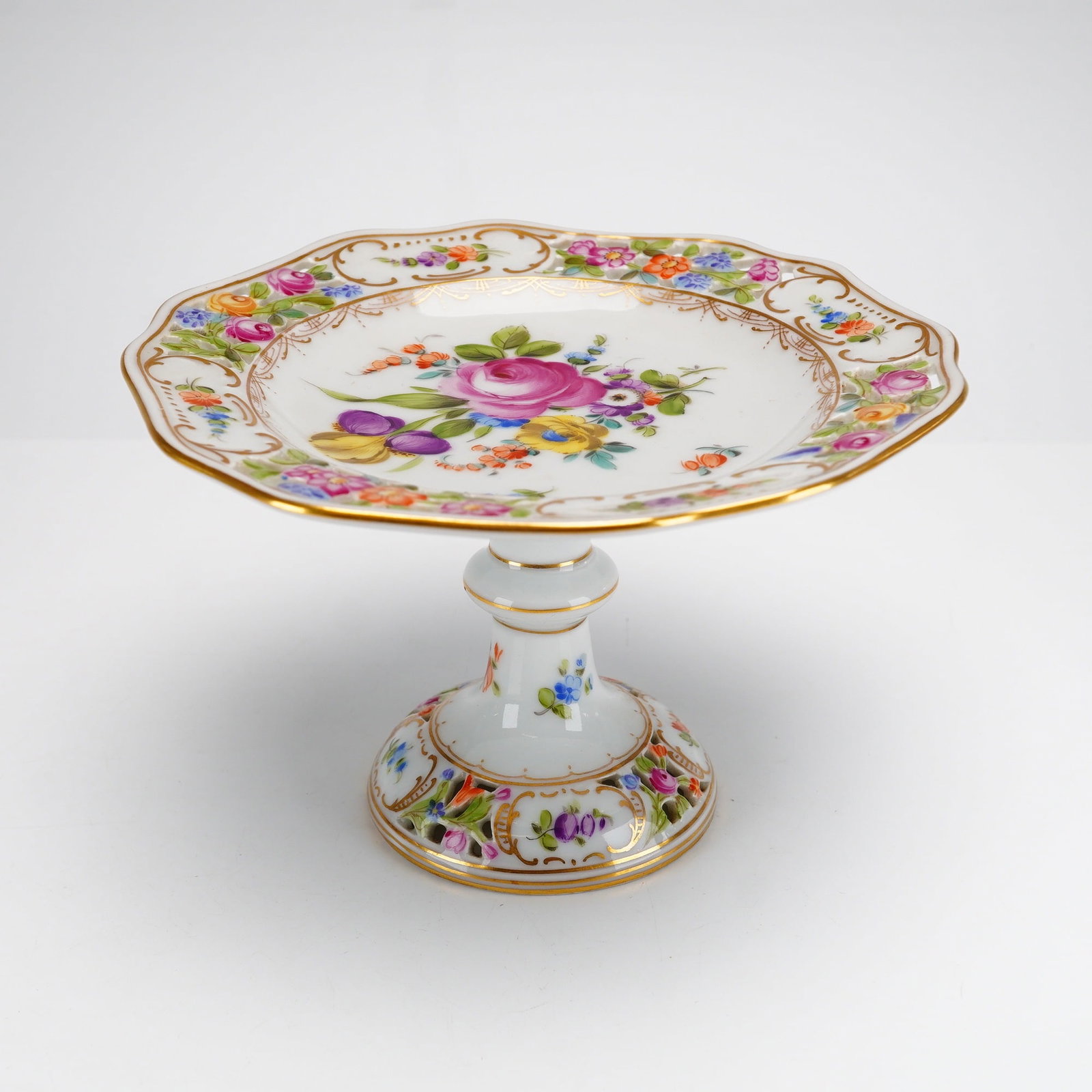 Carl Thieme Dresden Hand Painted Reticulated Porcelain Compote: This porcelain pedestal compote, produced by the Sachsische Porzellan-Manufaktur Dresden (Carl Thieme), features a tall form decorated with a hand painted floral design. The vessel is constructed with