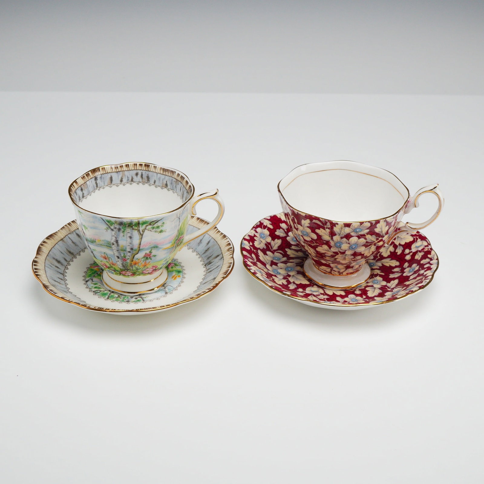 Two Royal Albert Bone China Cup and Saucer Sets Including Silver Birch Pattern: This collection includes two distinct bone china teacup and saucer sets manufactured by Royal Albert in England. The first set features the Silver Birch pattern, decorated with a pastoral landscape de