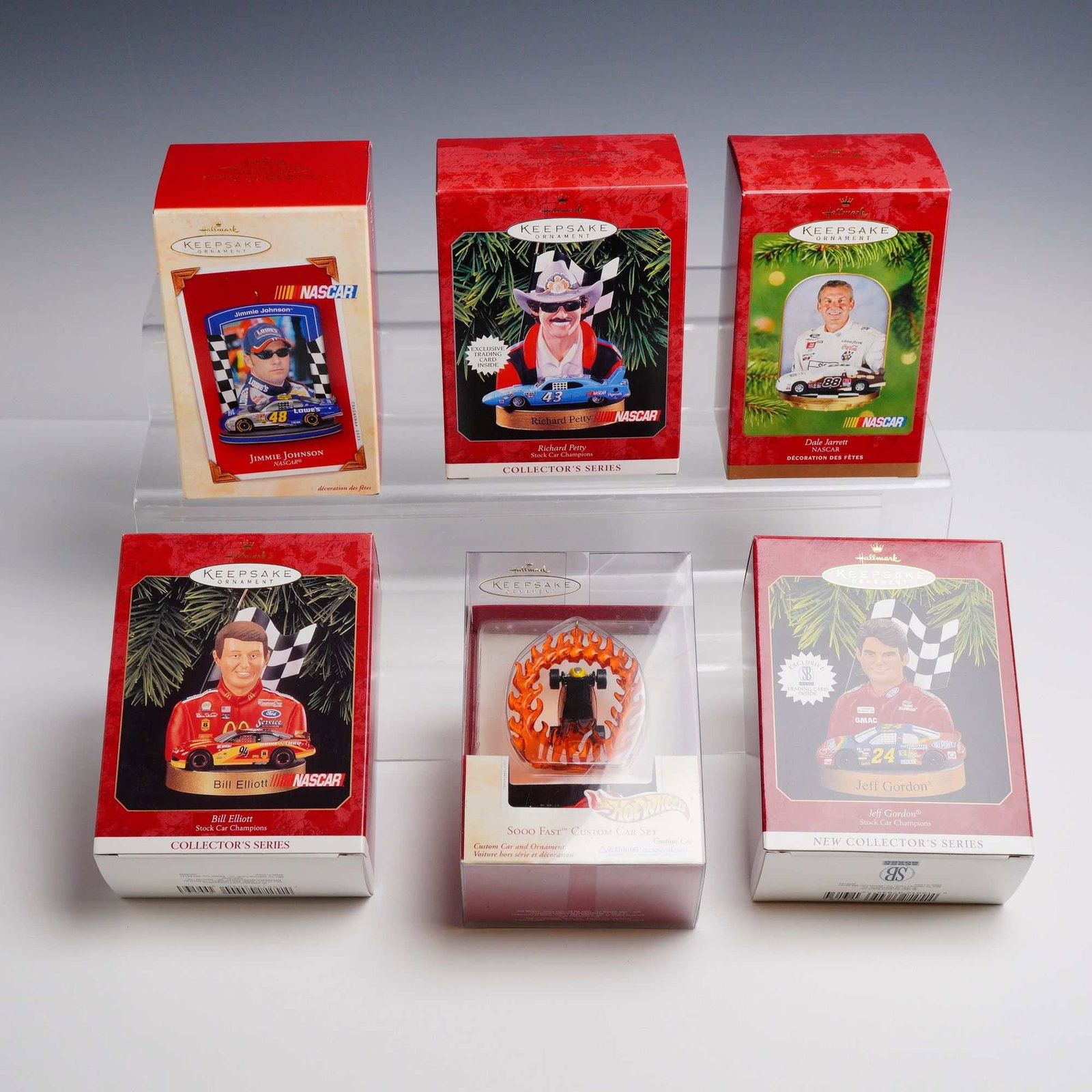 6pc Hallmark Keepsake NASCAR and Hot Wheels Ornaments: This lot features a collection of six Hallmark Keepsake ornaments themed around NASCAR drivers and racing. The items are housed in their original red retail boxes and are part of various series produc
