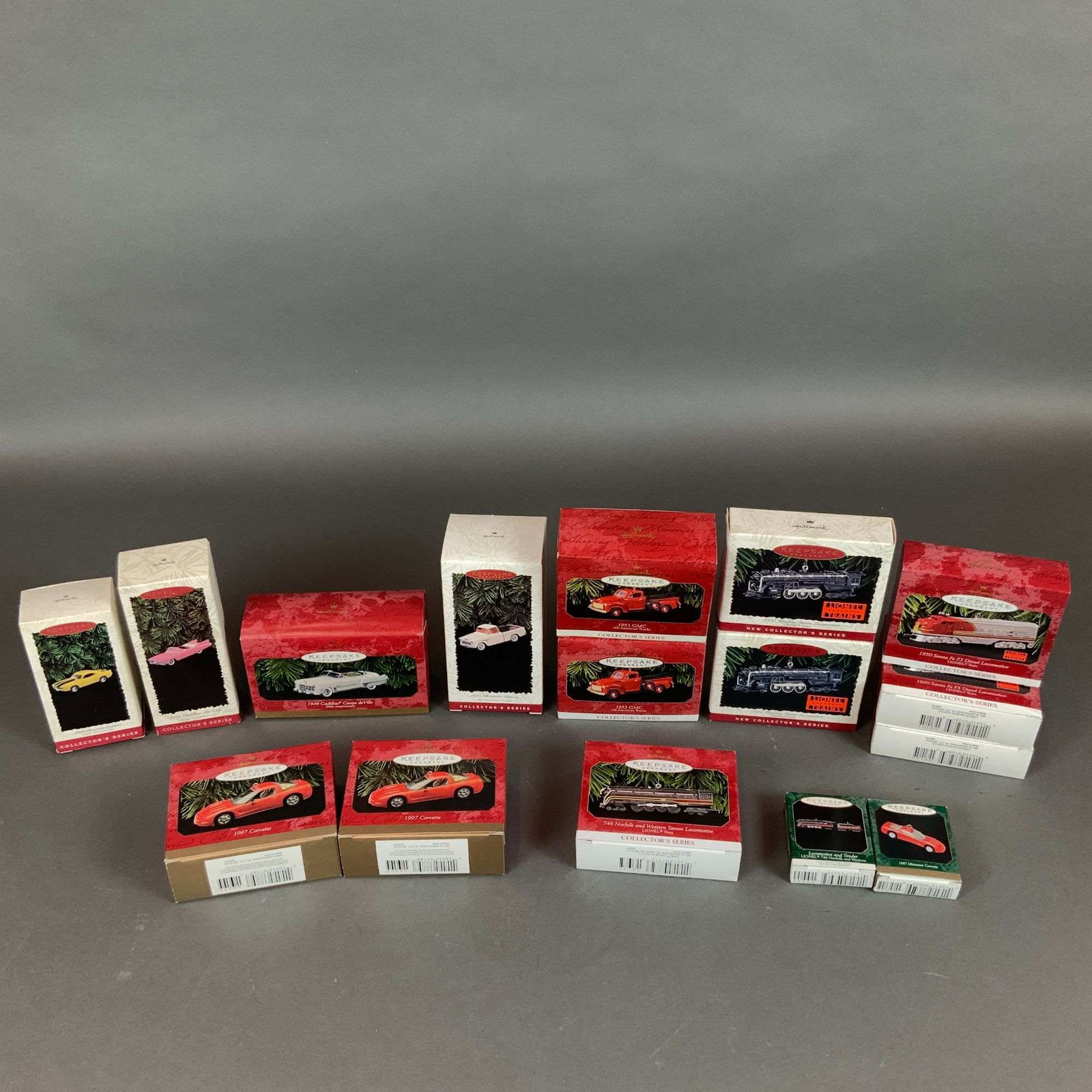 Collection of 16 Hallmark Keepsake Collector Series Vehicle and Train Ornaments: A collection of 16 Hallmark Keepsake ornaments from the Collector Series, primarily dating from the late 1990s. The group features a variety of automotive and locomotive models, including several 1997