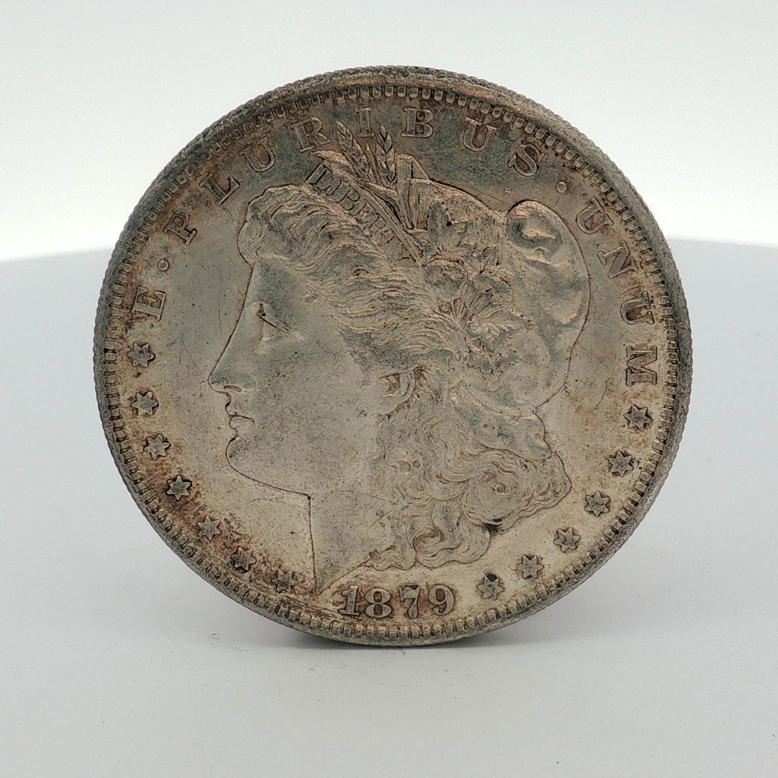 1879-S US Morgan Silver Dollar Coin: This US Morgan silver dollar is dated 1879 and was struck at the San Francisco mint, as indicated by the S mint mark located on the reverse above the denomination. The coin is composed of 90 percent s