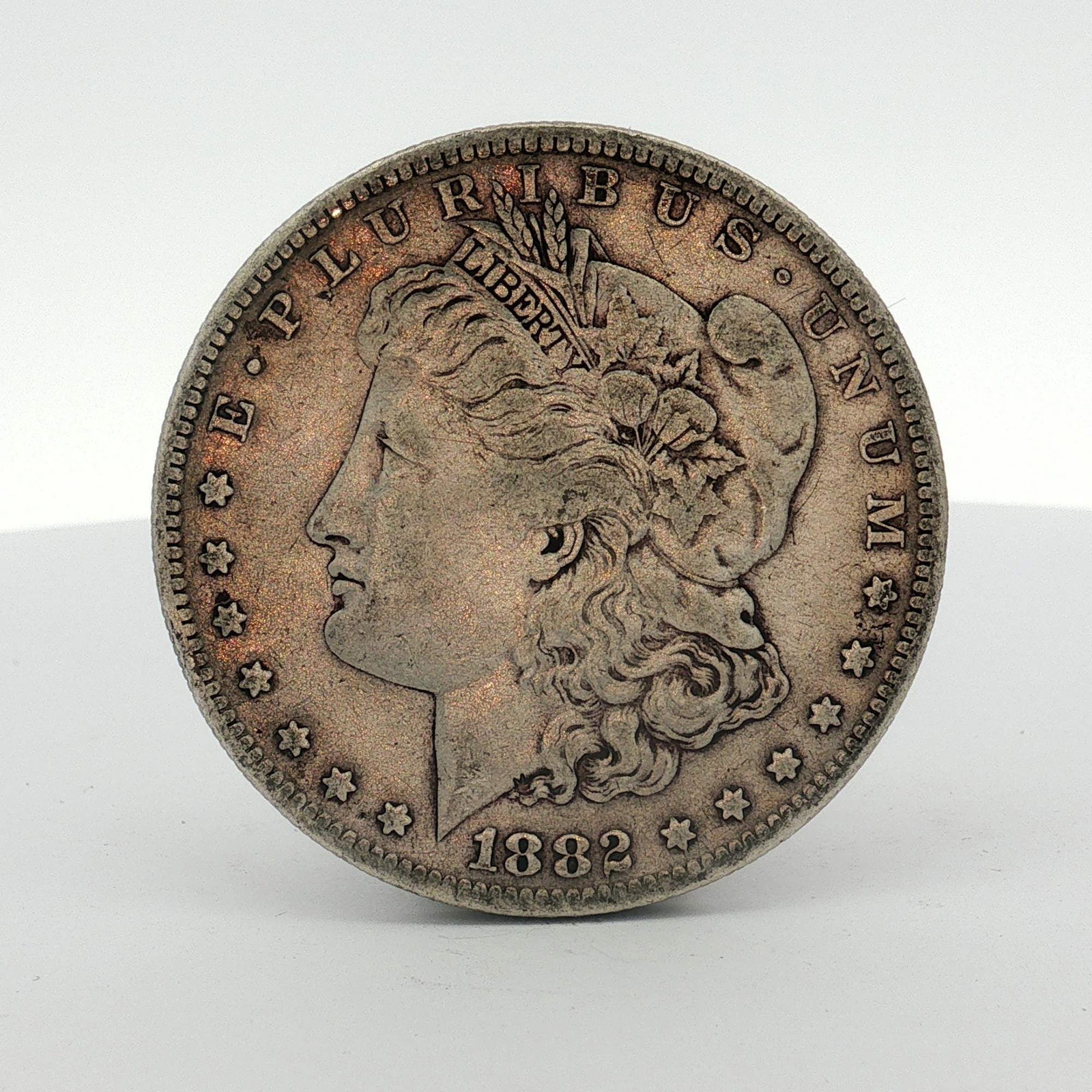 1882-S US One Dollar Morgan Silver Dollar, Circulated: This US 1882-S Morgan silver dollar is a struck 90 percent silver coin featuring the Liberty Head obverse and heraldic eagle reverse. Struck at the San Francisco Mint, it displays the S mint mark on t