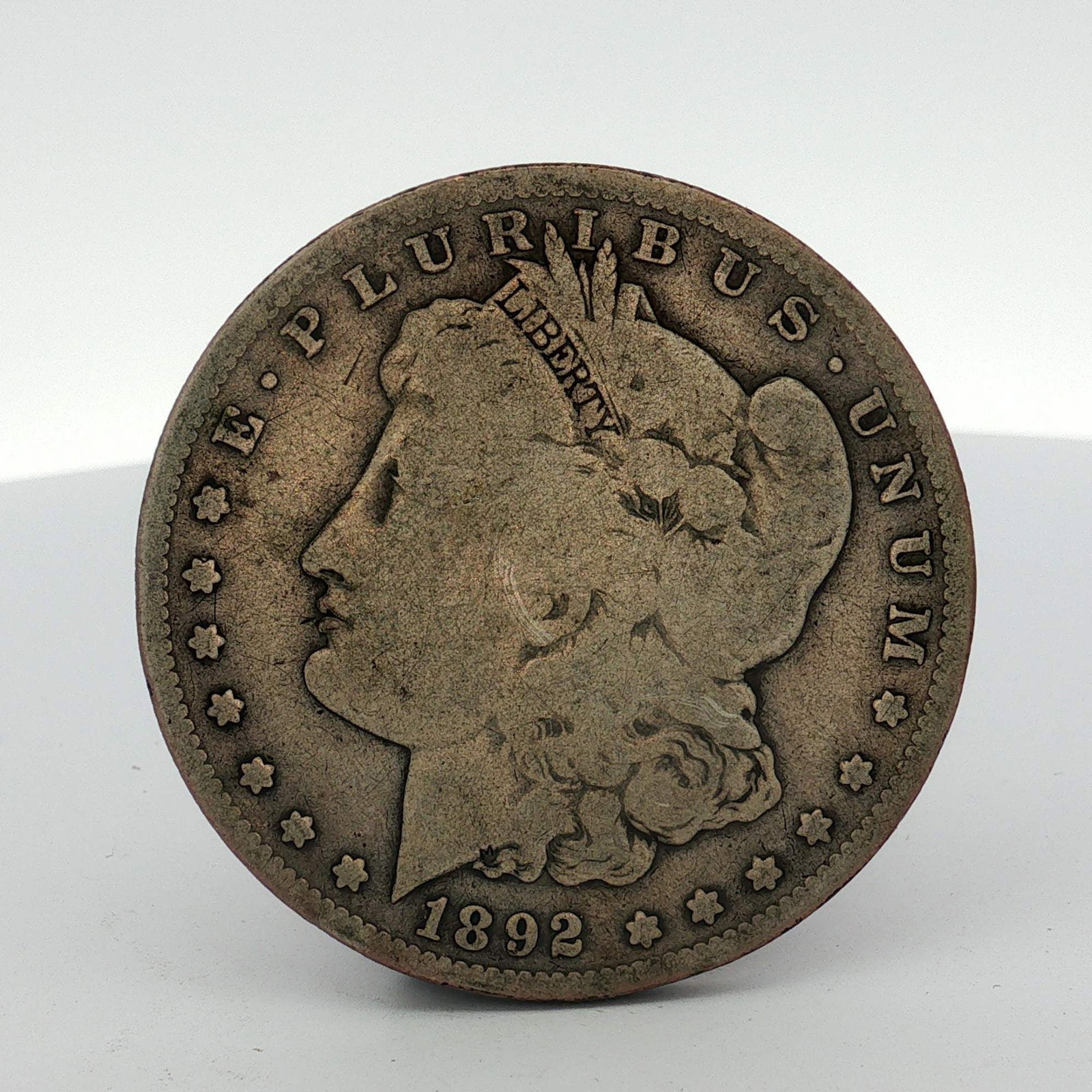 1892-S US Morgan Silver Dollar: This US Morgan dollar was struck in 1892 at the San Francisco Mint and is composed of 0.900 silver and 0.100 copper. The obverse features the Morgan dollar design with the date 1892 and the motto E