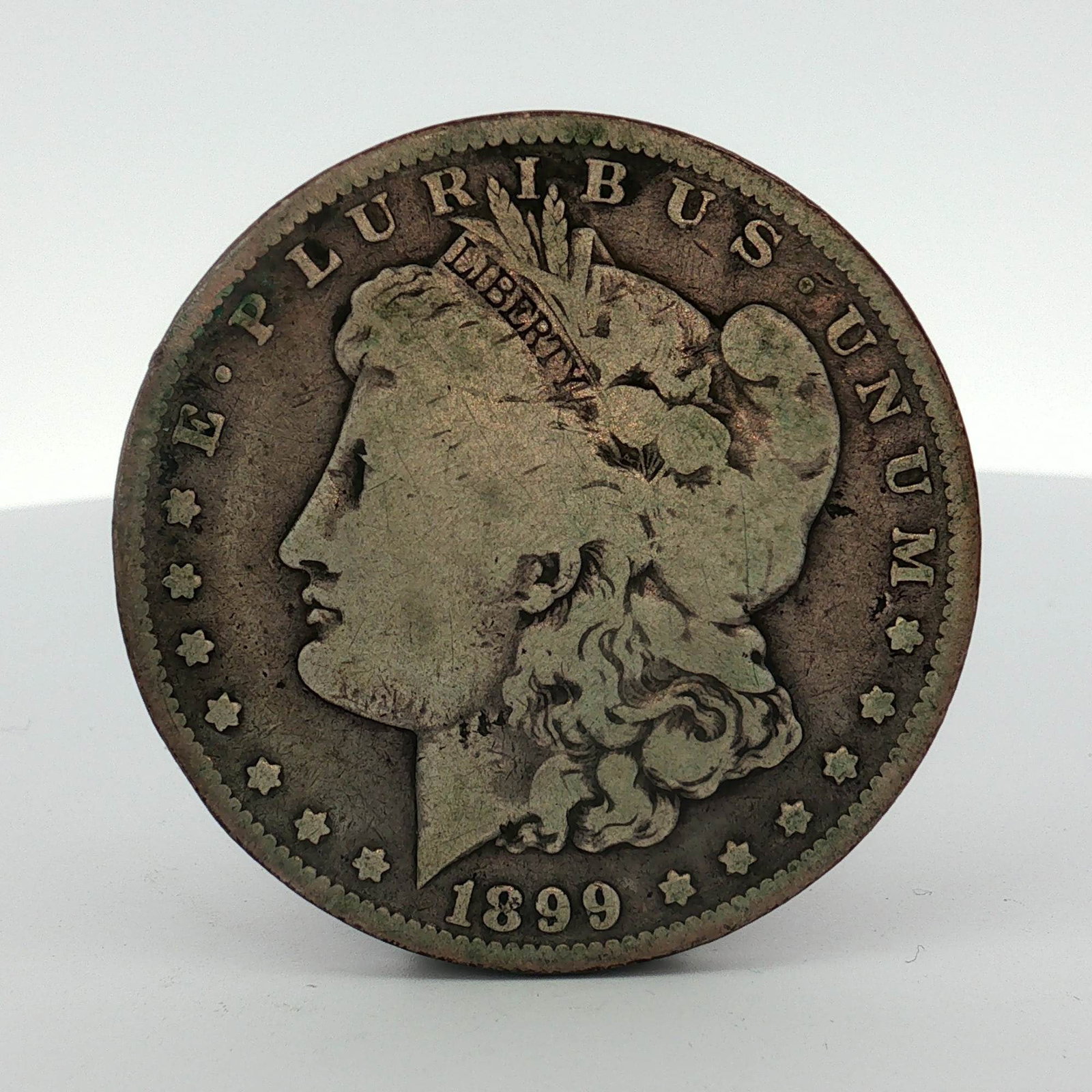 1899-O US Morgan Silver Dollar: This US 1899 Morgan dollar was struck at the New Orleans Mint. The coin is composed of 90 percent silver and 10 percent copper. It features the George T. Morgan Liberty obverse and eagle reverse desig