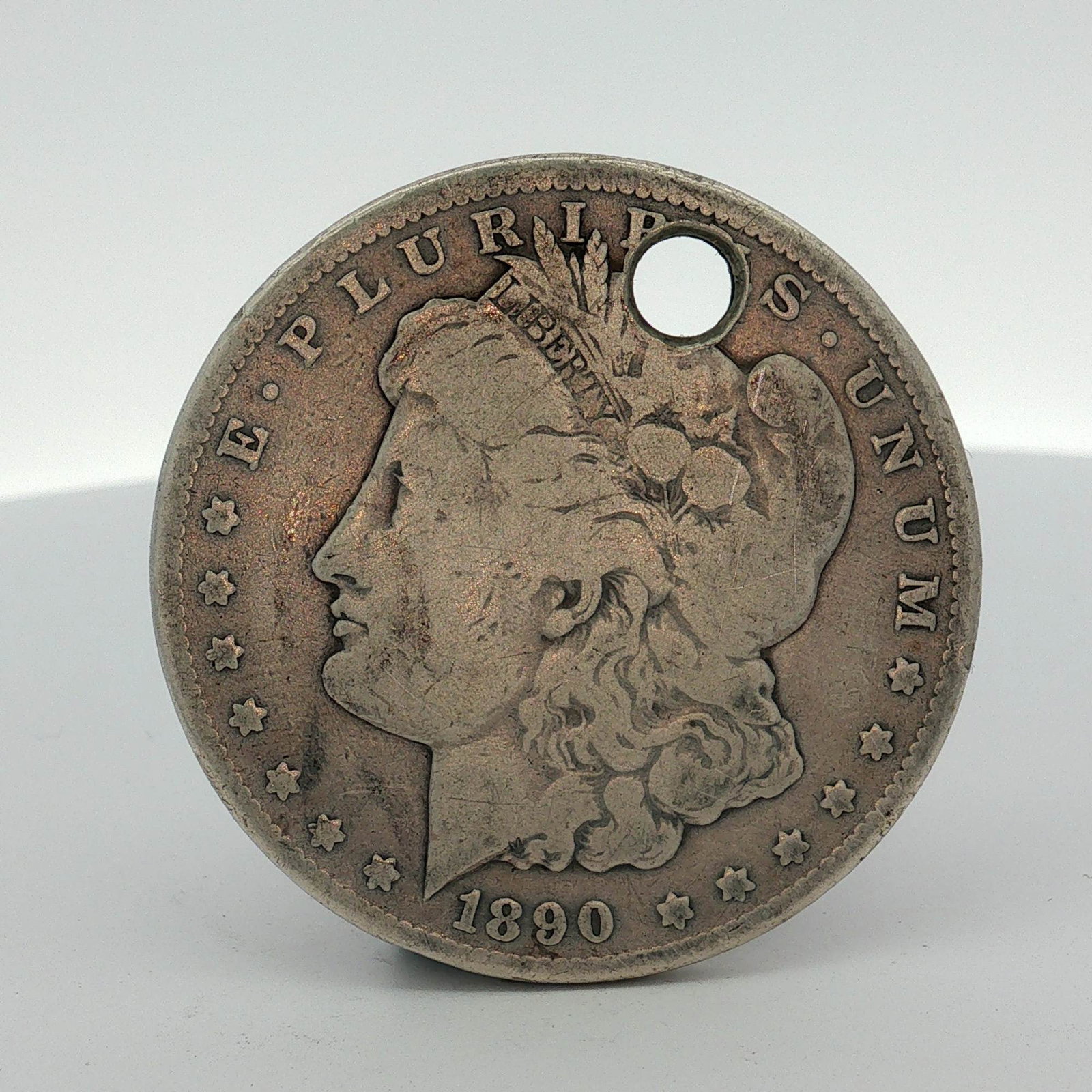 US 1890-CC Morgan Silver Dollar: This US Morgan silver dollar is a Carson City Mint issue. The composition is 90 percent silver and 10 percent copper with a reeded edge. The coin features the Morgan dollar design on the obverse with 