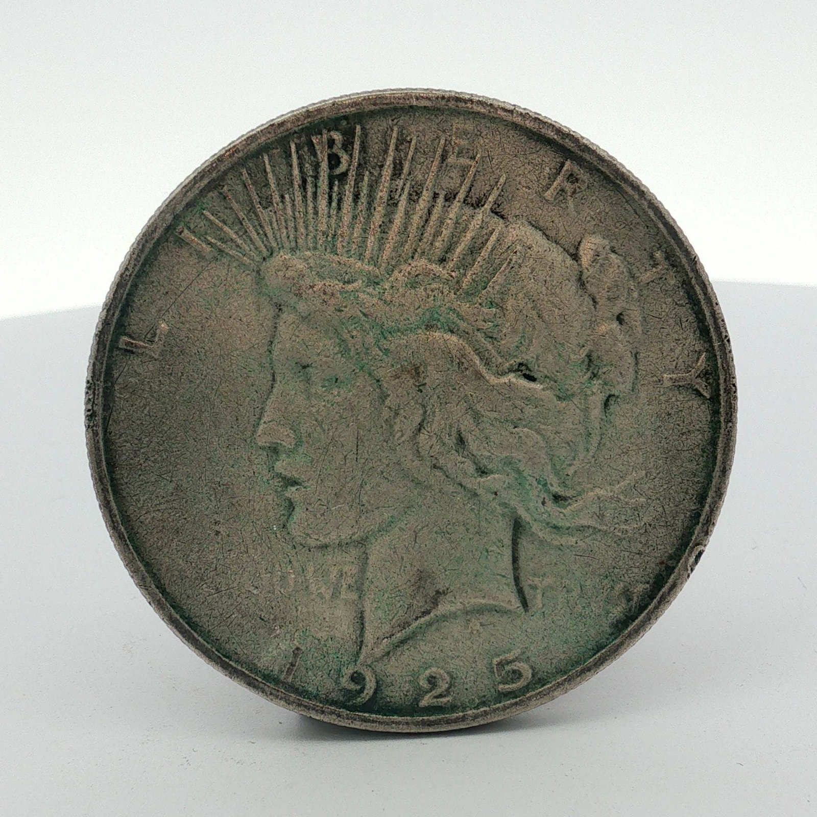 1925-S US One Doller Peace Silver Dollar Coin, Circulated: A US 1925-S Peace silver dollar composed of .900 fine silver. This specimen was struck at the San Francisco mint, as evidenced by the S mint mark on the reverse. The coin features the standard Peace d