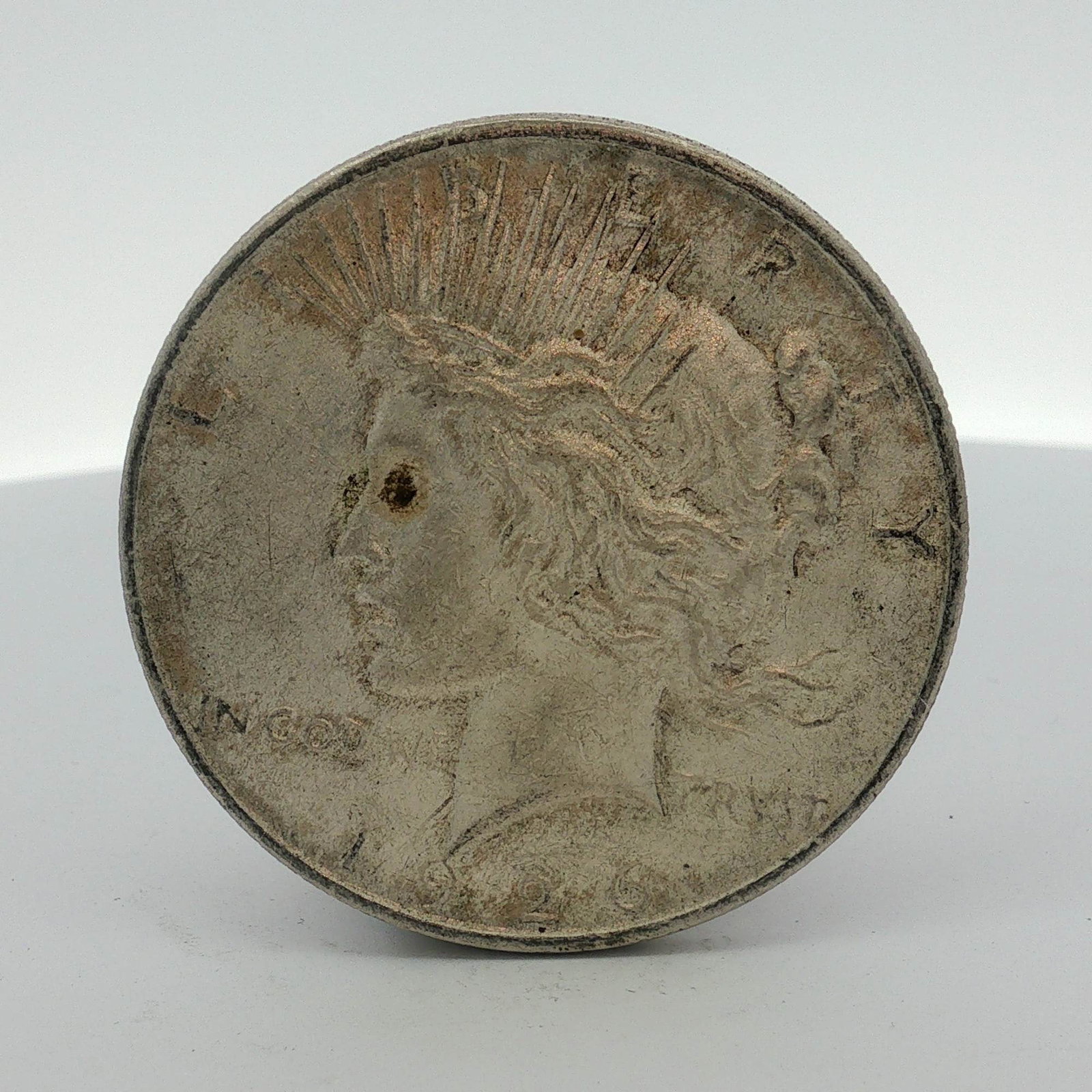 1926-D US One Dollar Peace Silver Dollar, Circulated: This 1926-D US Peace silver dollar was produced at the Denver Mint. The coin is composed of a 90 percent silver and 10 percent copper alloy. It features the standard Peace dollar design on the obverse