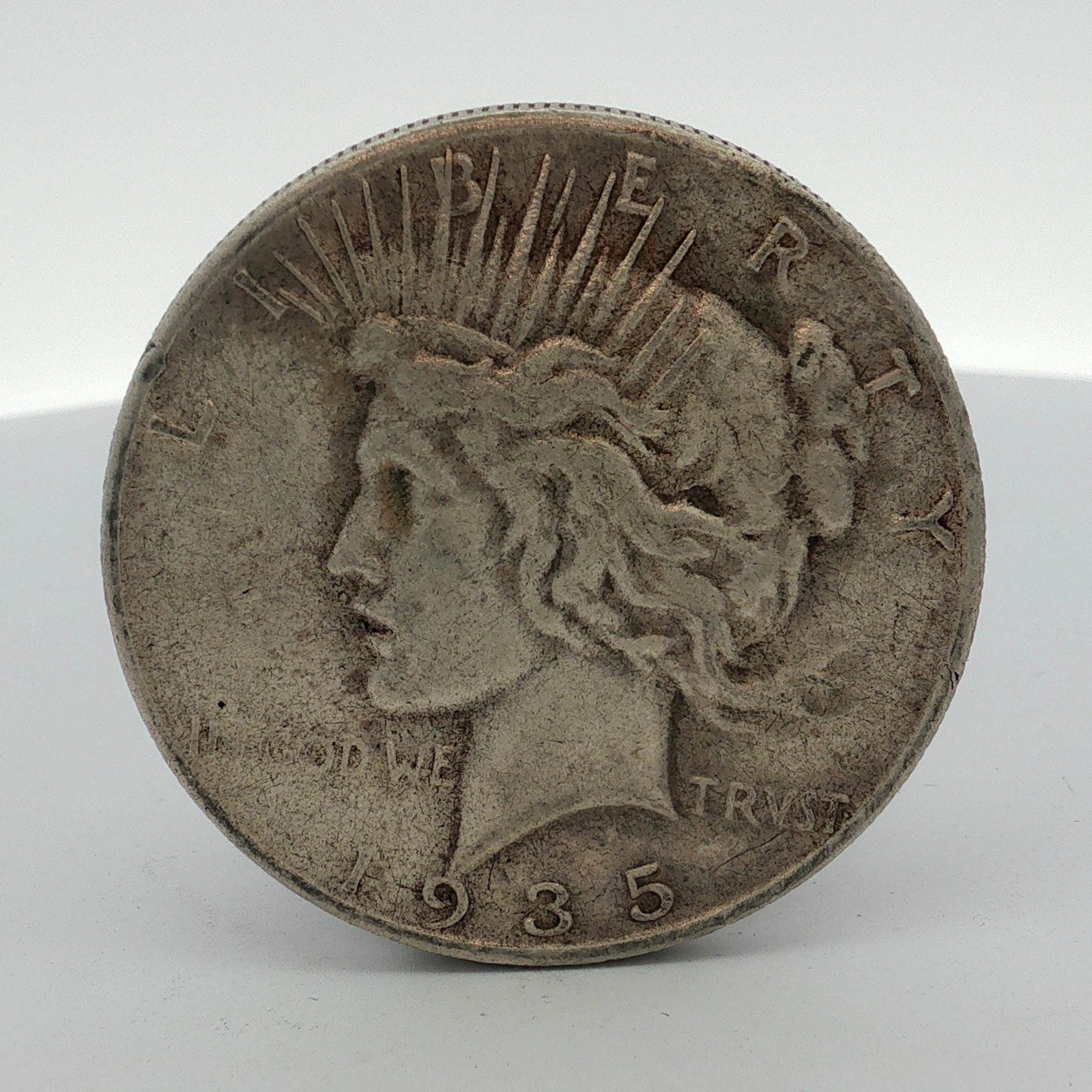 1935-S US One Dollar Peace Silver Dollar Coin, Circulated: US 1935-S Peace silver dollar struck in 0.900 fine silver. This coin features the standard Peace dollar obverse and reverse designs. The San Francisco Mint mark, a small S, is located on the reverse n
