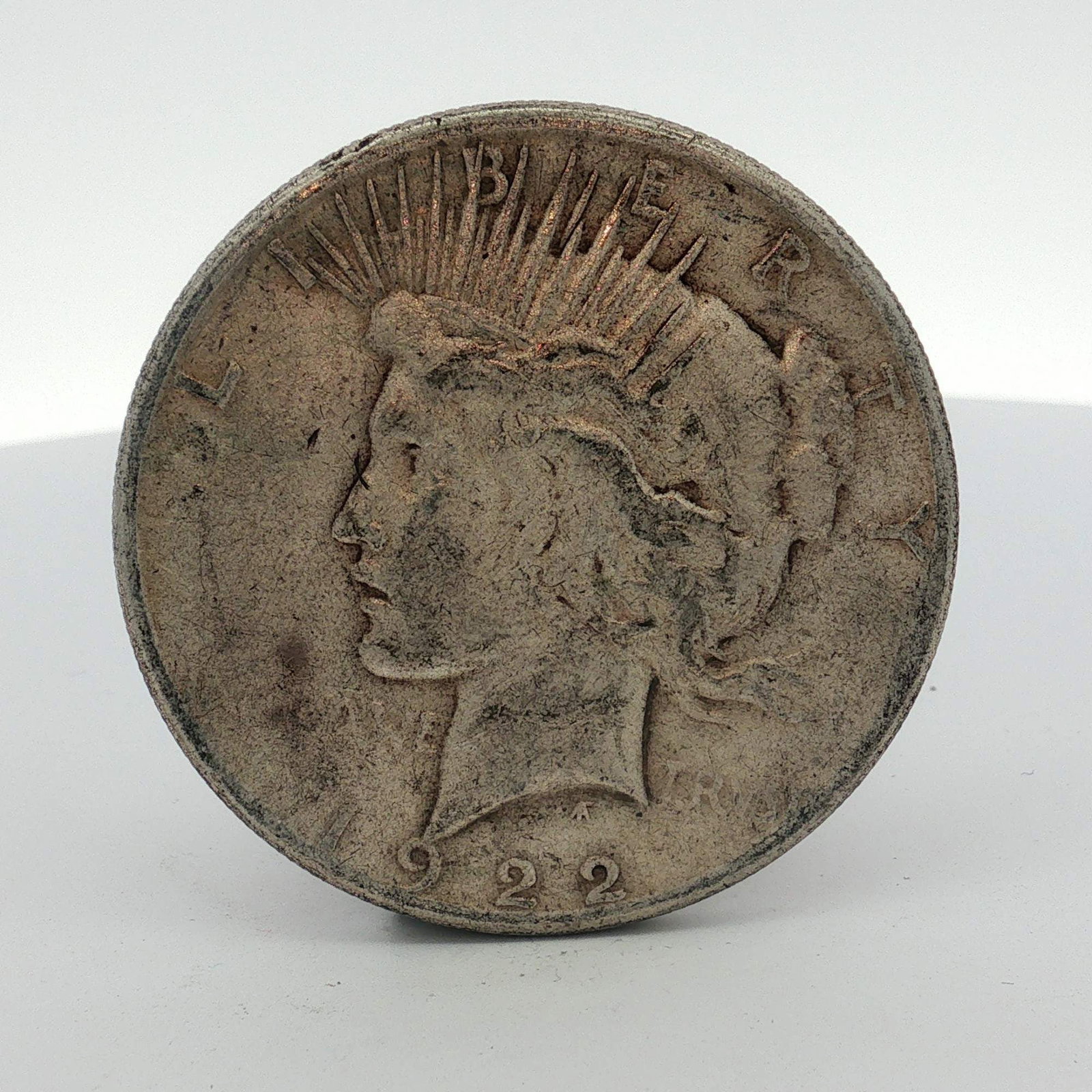 1922 US Peace Silver Dollar: 1922 US Peace silver dollar struck at the Philadelphia Mint. This Peace dollar is composed of 90% silver and 10% copper. The coin features the standard Peace dollar obverse and reverse designs and is 