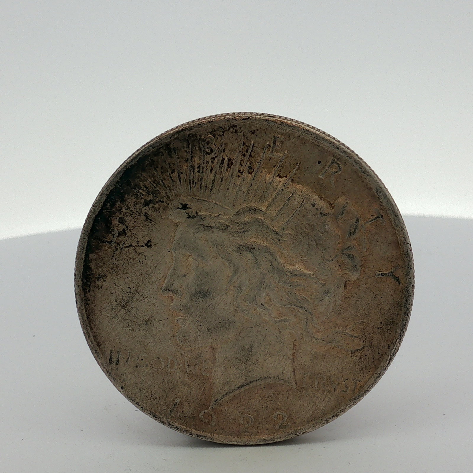 1922 US Peace Silver Dollar: This 1922 US Peace silver dollar is composed of 90 percent silver and 10 percent copper. The obverse features the Peace dollar design with a left-facing profile of Liberty wearing a radiate crown, wit