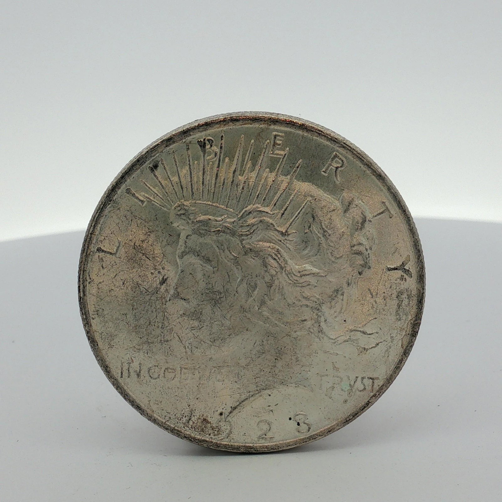 1923 US Peace Silver Dollar: This is a 1923 US Peace silver dollar struck at the Philadelphia Mint. The coin is composed of 90% silver and 10% copper and features a reeded edge. It displays the Peace Dollar obverse and Peace Doll