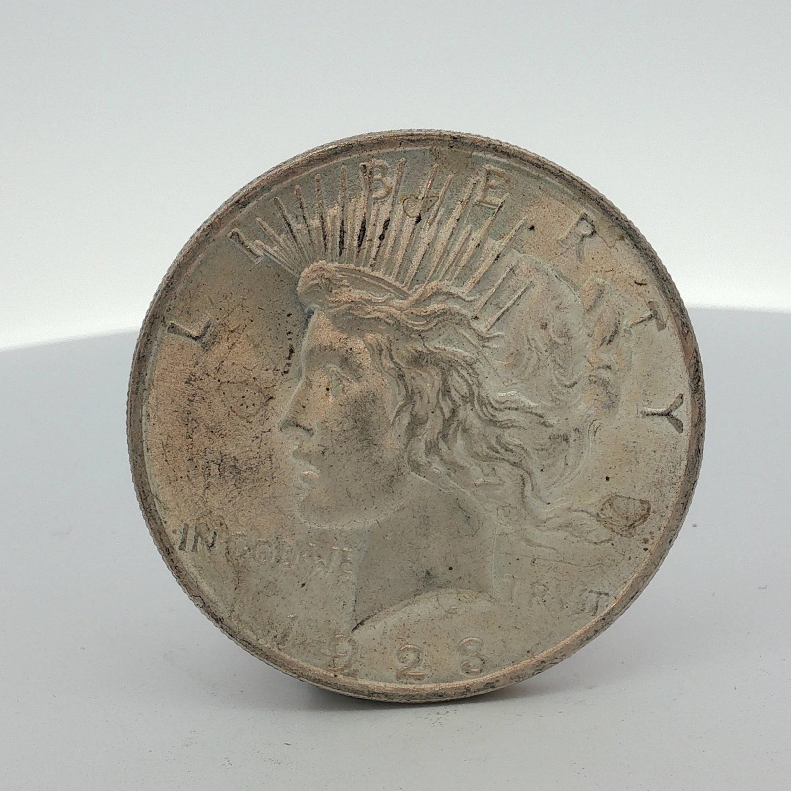 1923 US Peace Silver Dollar: This 1923 US Peace silver dollar is a struck 90% silver coin produced at the Philadelphia Mint. The obverse features the standard Peace dollar design type, dated 1923. The reverse features the standar