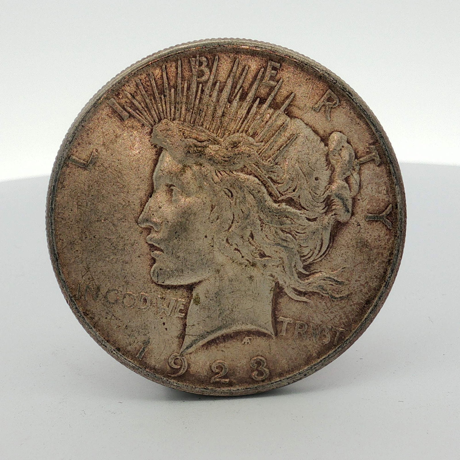 1923 US Peace Silver Dollar: This 1923 US Peace silver dollar was struck at the Philadelphia Mint. The coin is composed of 90 percent silver and 10 percent copper. The obverse features Liberty wearing a radiate crown with the ins