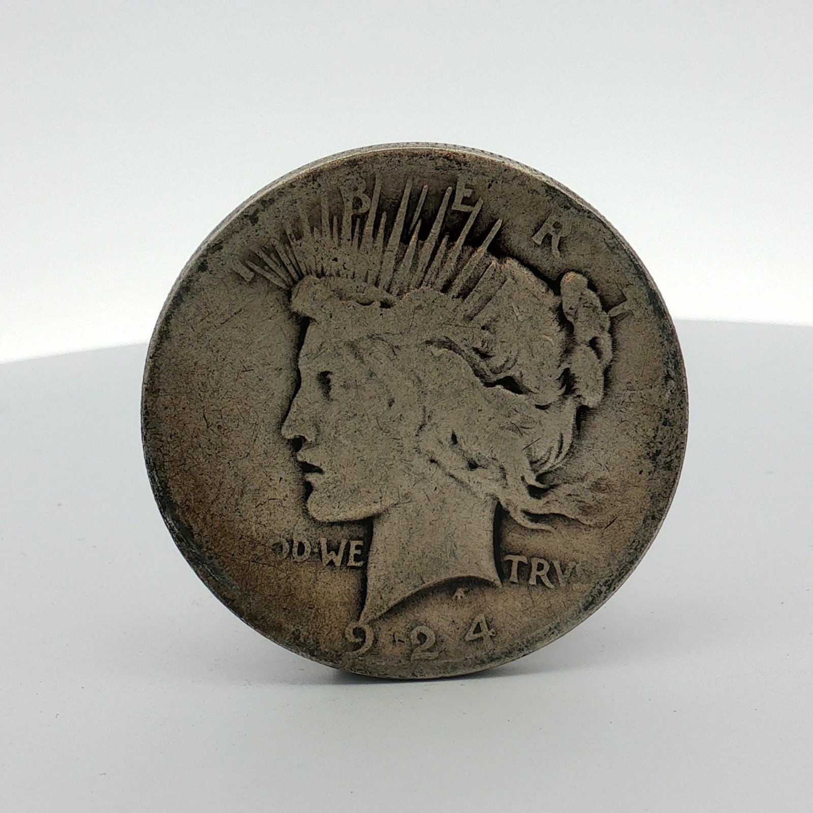 1924 US Peace Silver Dollar: This 1924 US Peace silver dollar was struck at the Philadelphia Mint. The composition is 90 percent silver and 10 percent copper. The coin features the Peace Dollar obverse and reverse designs. Inscri