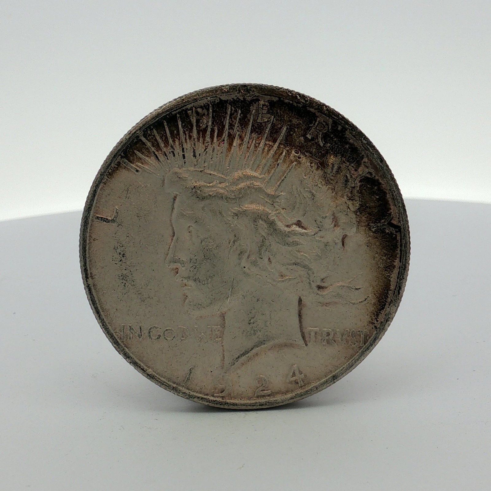 1924 US Peace Silver Dollar: A 1924 US Peace silver dollar, struck at the Philadelphia Mint. This silver coin features the standard Peace dollar obverse and reverse design types. The obverse bears the inscriptions LIBERTY, IN GOD