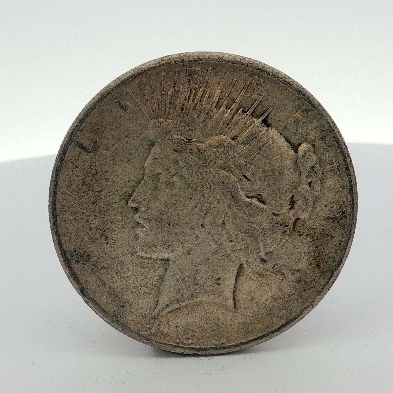 1925-S US Peace Silver Dollar: This US Peace silver dollar is composed of silver. The obverse features the Peace design showing the profile of Liberty with a radiate crown. The reverse displays the Peace design with an eagle perche