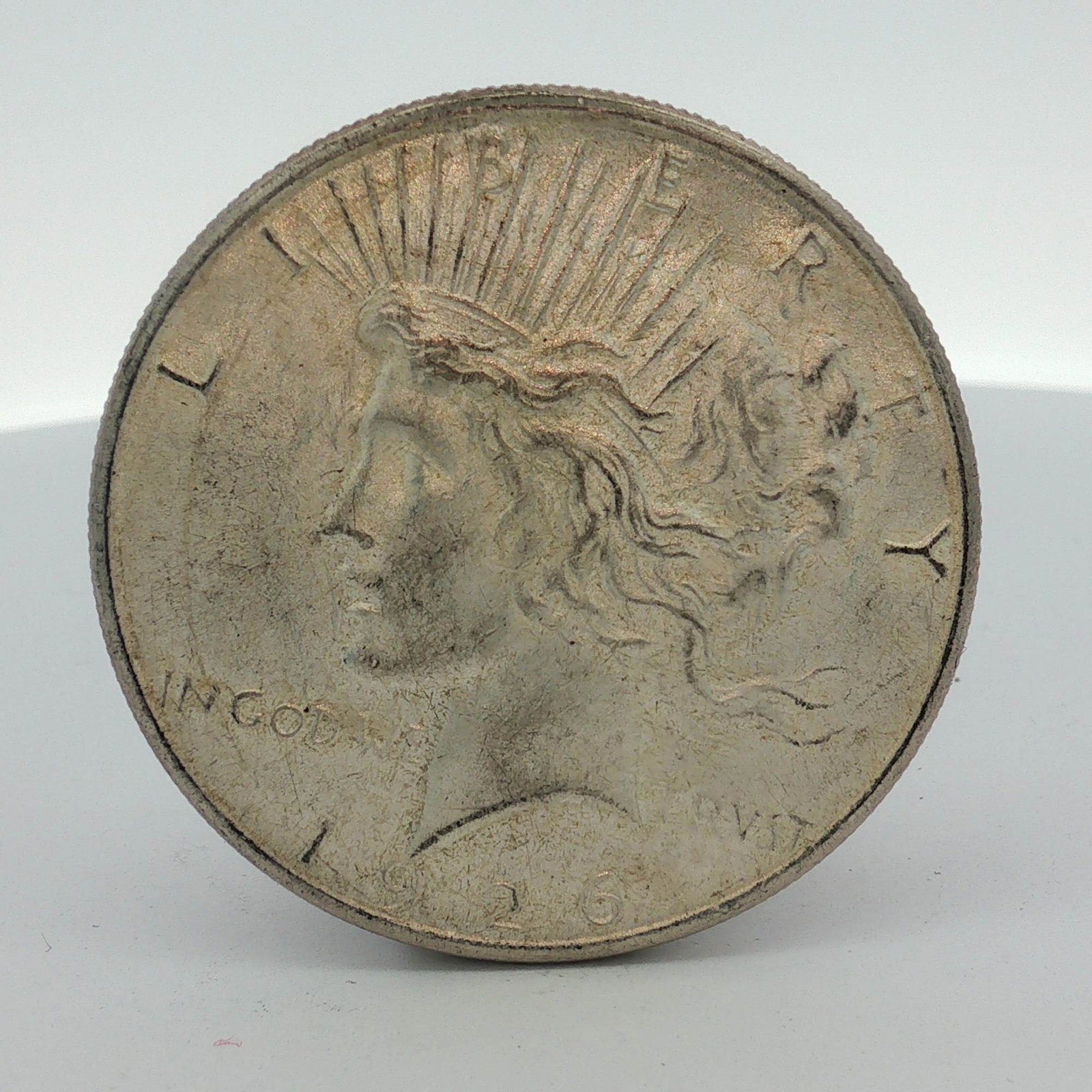 1926 US Silver Peace Dollar: This 1926 US silver Peace dollar is a struck coin composed of 90% silver. The obverse features the standard Peace dollar design type with inscriptions LIBERTY, IN GOD WE TRVST, and the date 1926. The 